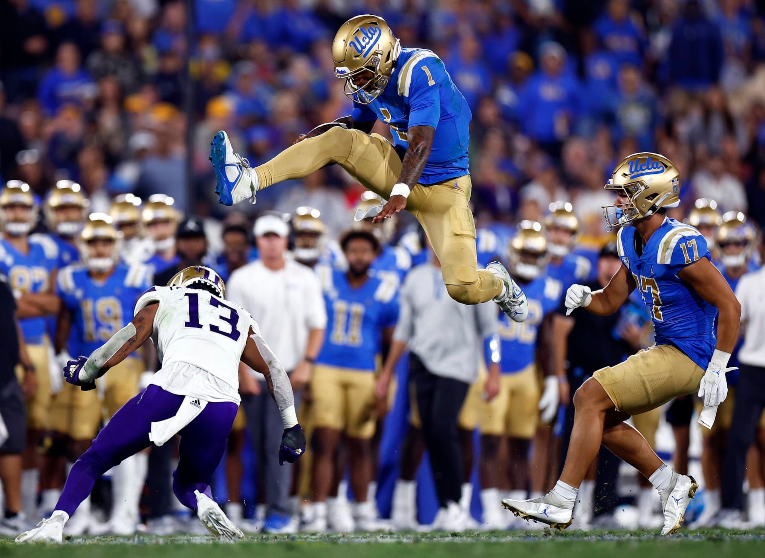 PASADENA, CALIFORNIA - SEPTEMBER 30:  Dorian Thompson-Robinson #1 of the UCLA Bruins jumps over Kamren Fabiculanan #13 of the Washington Huskies in the second quarter at Rose Bowl Stadium on September 30, 2022 in Pasadena, California. (Photo by Ronald Martinez/Getty Images)