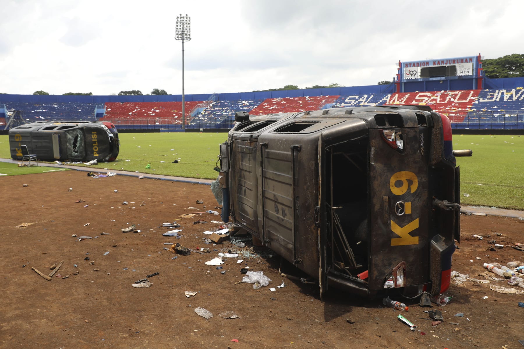Police cars lie on their side wrecked on the pitch at Kanjuruhan Stadium in Malang, East Java, Indonesia, Sunday, Oct. 2, 2022. Panic at an Indonesian soccer match Saturday left over 100 people dead, most of whom were trampled to death after police fired tear gas to prevent violence. (AP Photo/Trisnadi) Police cars lie on their side wrecked on the pitch at Kanjuruhan Stadium in Malang, East Java, Indonesia, Sunday, Oct. 2, 2022. Panic at an Indonesian soccer match Saturday left over 100 people dead, most of whom were trampled to death after police fired tear gas to prevent violence. (AP Photo/Trisnadi)