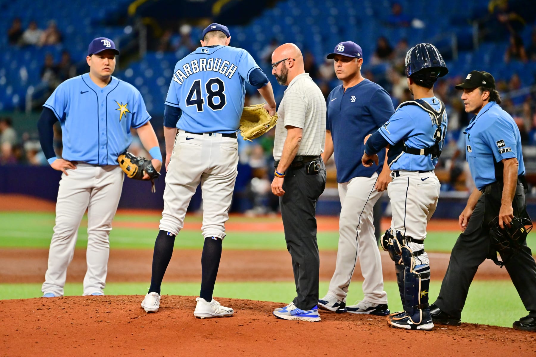 ST PETERSBURG, FLORIDA - SEPTEMBER 22: Ryan Yarbrough #48 of the Tampa Bay Rays meets with manager Kevin Cash #16 and a trainer before exiting the game in the second inning against the Toronto Blue Jays at Tropicana Field on September 22, 2022 in St Petersburg, Florida. (Photo by Julio Aguilar/Getty Images)