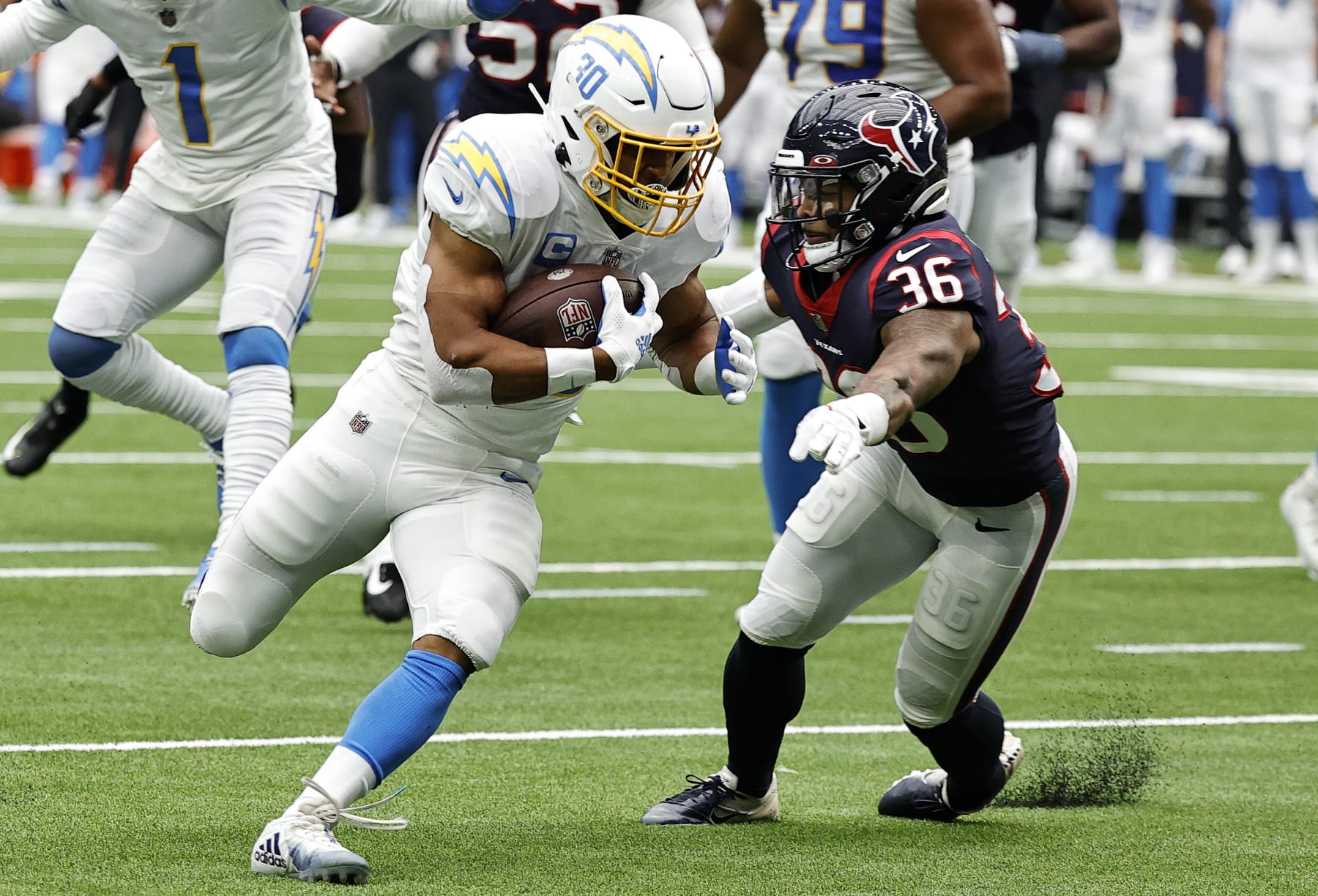 HOUSTON, TEXAS - OCTOBER 02: Austin Ekeler #30 of the Los Angeles Chargers runs with the ball while being chased by Jonathan Owens #36 of the Houston Texans in the second quarter at NRG Stadium on October 02, 2022 in Houston, Texas. (Photo by Bob Levey/Getty Images)