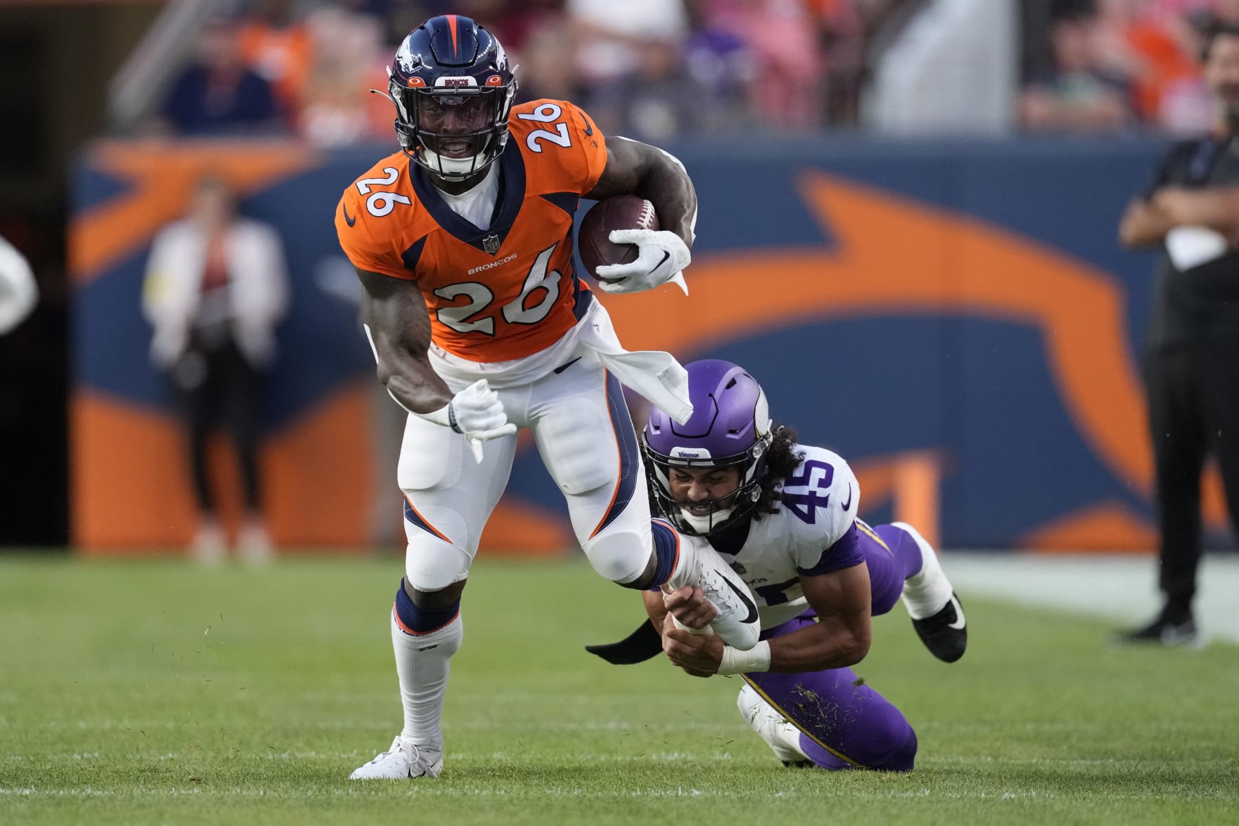 Denver Broncos running back Mike Boone (26) eludes the tackle of Minnesota Vikings linebacker Troy Dye (45) during the first half of an NFL preseason football game, Saturday, Aug. 27, 2022, in Denver. (AP Photo/David Zalubowski)