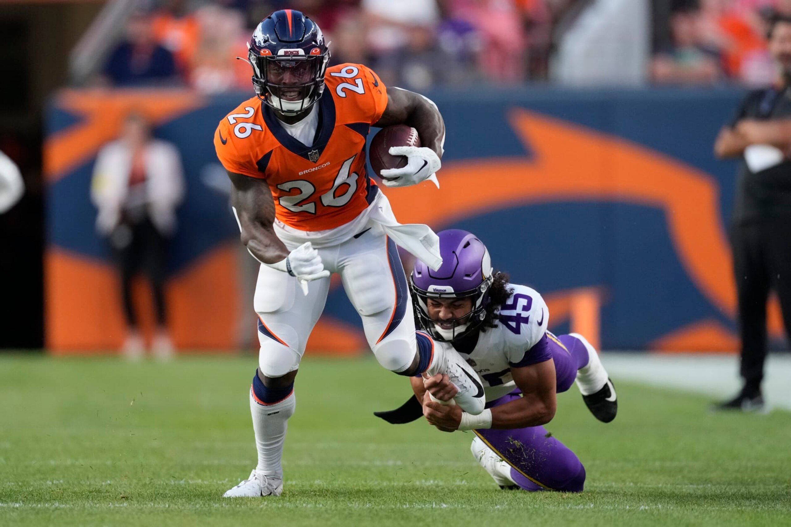 Denver Broncos running back Mike Boone (26) eludes the tackle of Minnesota Vikings linebacker Troy Dye (45) during the first half of an NFL preseason football game, Saturday, Aug. 27, 2022, in Denver. (AP Photo/David Zalubowski)