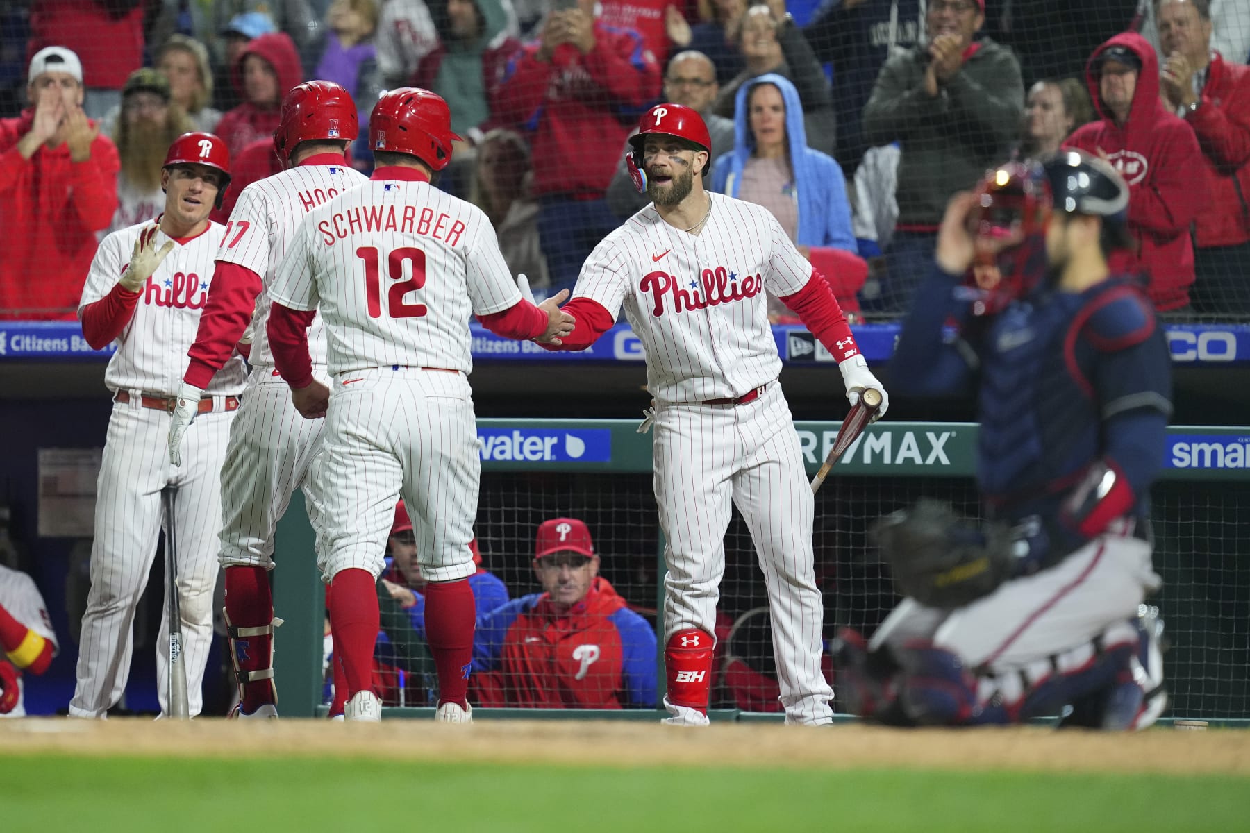 PHILADELPHIA, PA - SEPTEMBER 23: J.T. Realmuto #10, Rhys Hoskins #17, Kyle Schwarber #12, and Bryce Harper #3 of the Philadelphia Phillies react after a two run home run by Hoskins in the bottom fourth inning against the Atlanta Braves at Citizens Bank Park on September 23, 2022 in Philadelphia, Pennsylvania. The Phillies defeated the Braves 9-1. (Photo by Mitchell Leff/Getty Images)