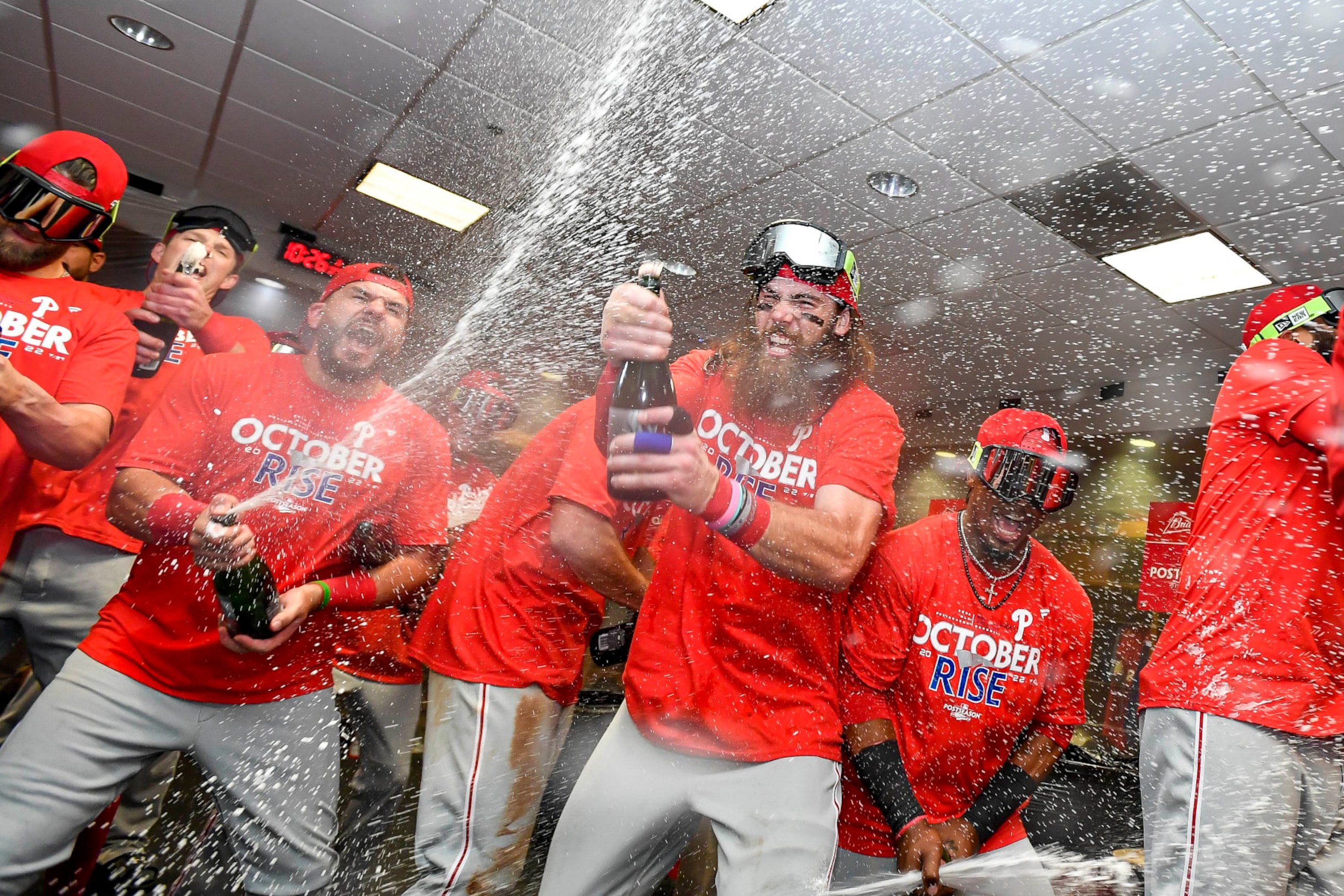HOUSTON, TEXAS - OCTOBER 03: Kyle Schwarber #12 and Brandon Marsh #16 of the Philadelphia Phillies celebrate in the locker room with their teammates after defeating the Houston Astros to clinch the Wild Card at Minute Maid Park on October 03, 2022 in Houston, Texas. (Photo by Logan Riely/Getty Images)