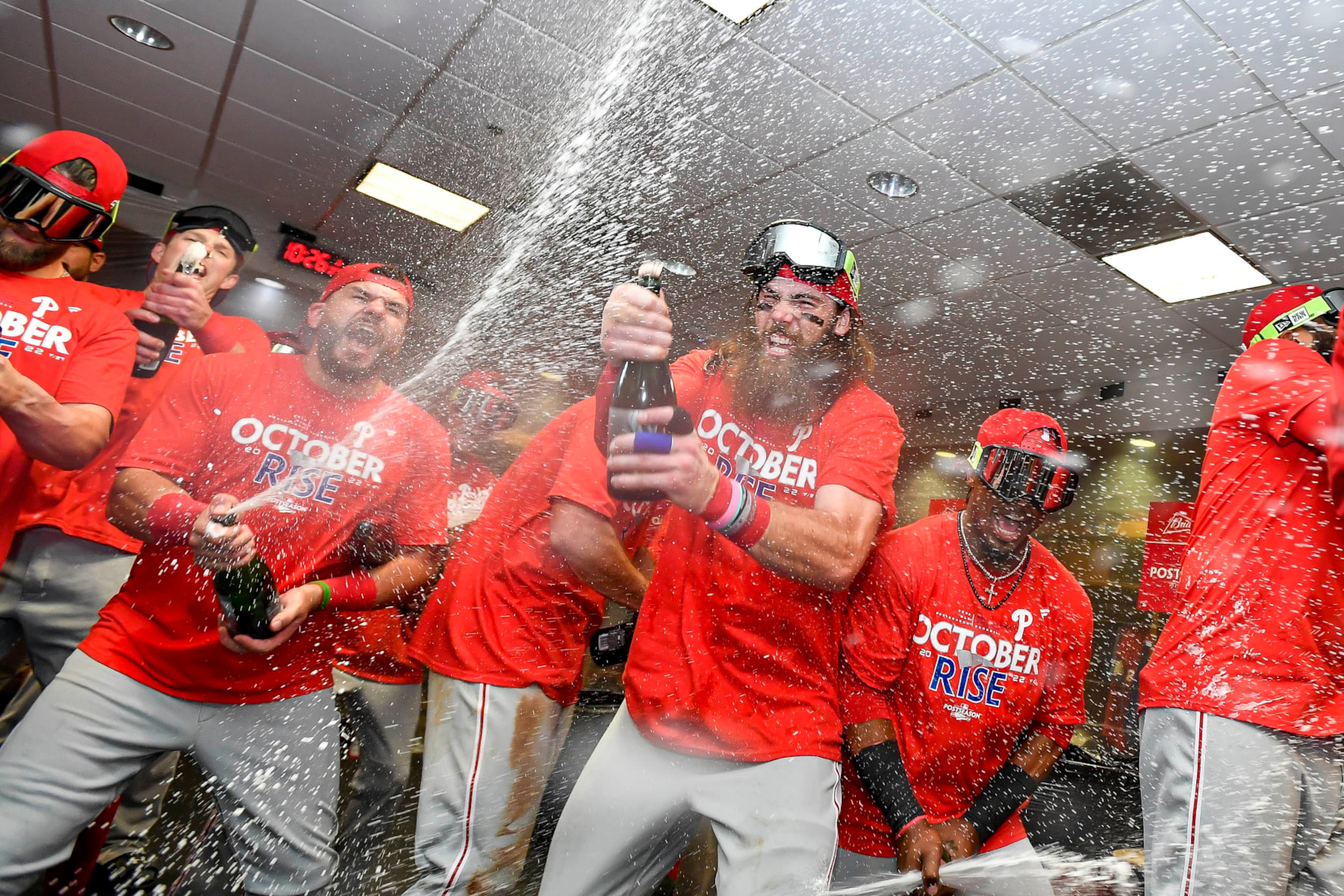 HOUSTON, TEXAS - OCTOBER 03: Kyle Schwarber #12 and Brandon Marsh #16 of the Philadelphia Phillies celebrate in the locker room with their teammates after defeating the Houston Astros to clinch the Wild Card at Minute Maid Park on October 03, 2022 in Houston, Texas. (Photo by Logan Riely/Getty Images)