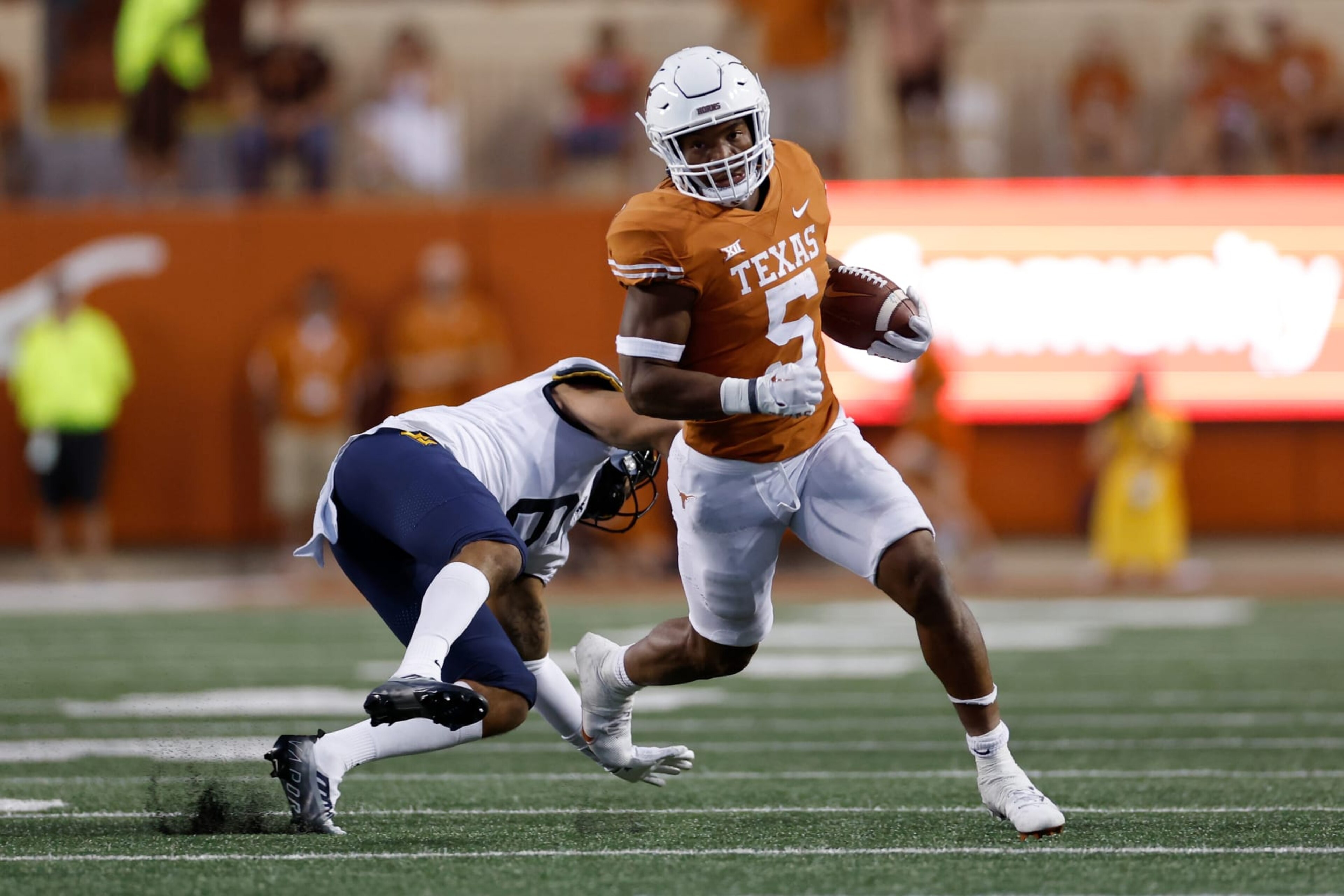 AUSTIN, TEXAS - OCTOBER 01: Bijan Robinson #5 of the Texas Longhorns breaks a tackle attempt by Exree Loe #6 of the West Virginia Mountaineers in the second quarter at Darrell K Royal-Texas Memorial Stadium on October 01, 2022 in Austin, Texas. (Photo by Tim Warner/Getty Images) AUSTIN, TEXAS - OCTOBER 01: Bijan Robinson #5 of the Texas Longhorns breaks a tackle attempt by Exree Loe #6 of the West Virginia Mountaineers in the second quarter at Darrell K Royal-Texas Memorial Stadium on October 01, 2022 in Austin, Texas. (Photo by Tim Warner/Getty Images)
