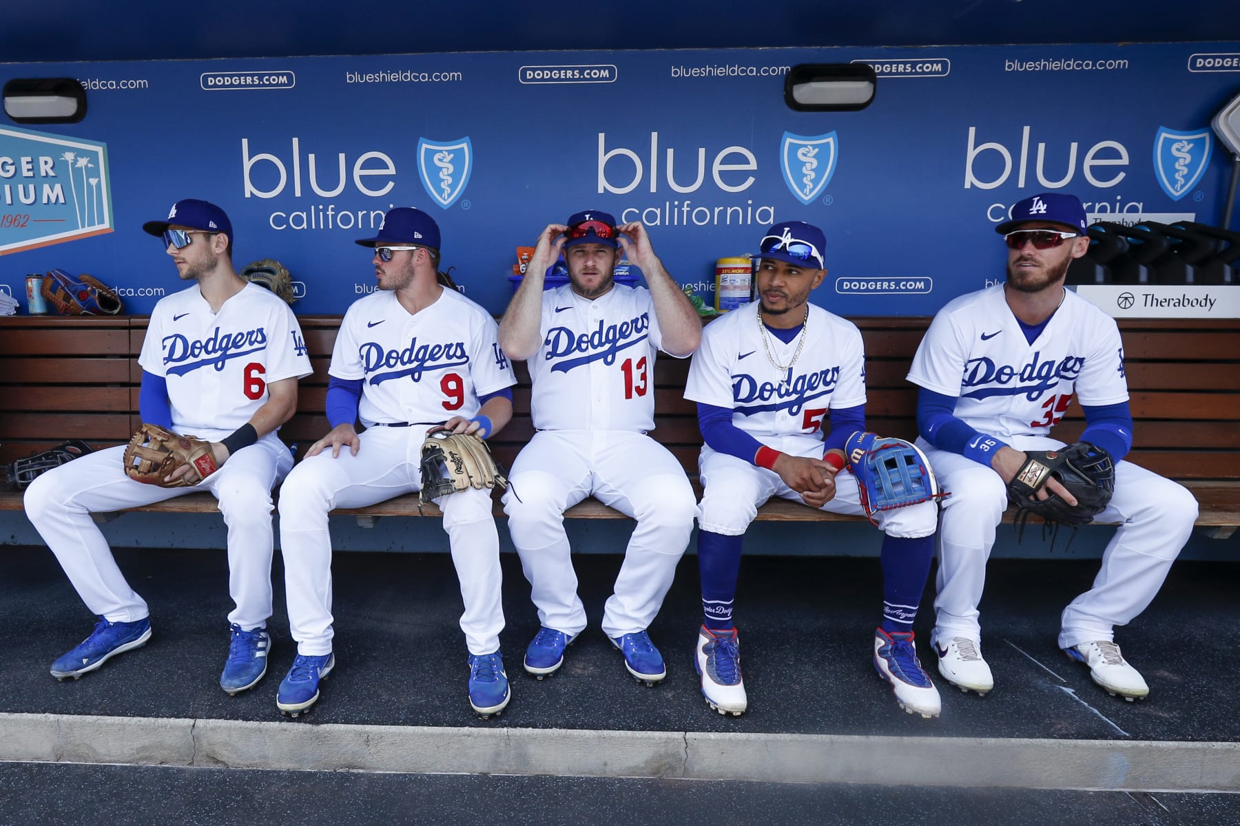 LOS ANGELES, CA - JULY 24: Los Angeles Dodgers first baseman Freddie Freeman (5), shortstop Trea Turner (6), second baseman Gavin Lux (9),  third baseman Max Muncy (13), right fielder Mookie Betts (50), and center fielder Cody Bellinger (35) sit in the dugout prior to a regular season game between the San Francisco Giants and Los Angeles Dodgers on July 24, 2022, at Dodger Stadium in Los Angeles, CA. (Photo by Brandon Sloter/Icon Sportswire via Getty Images)