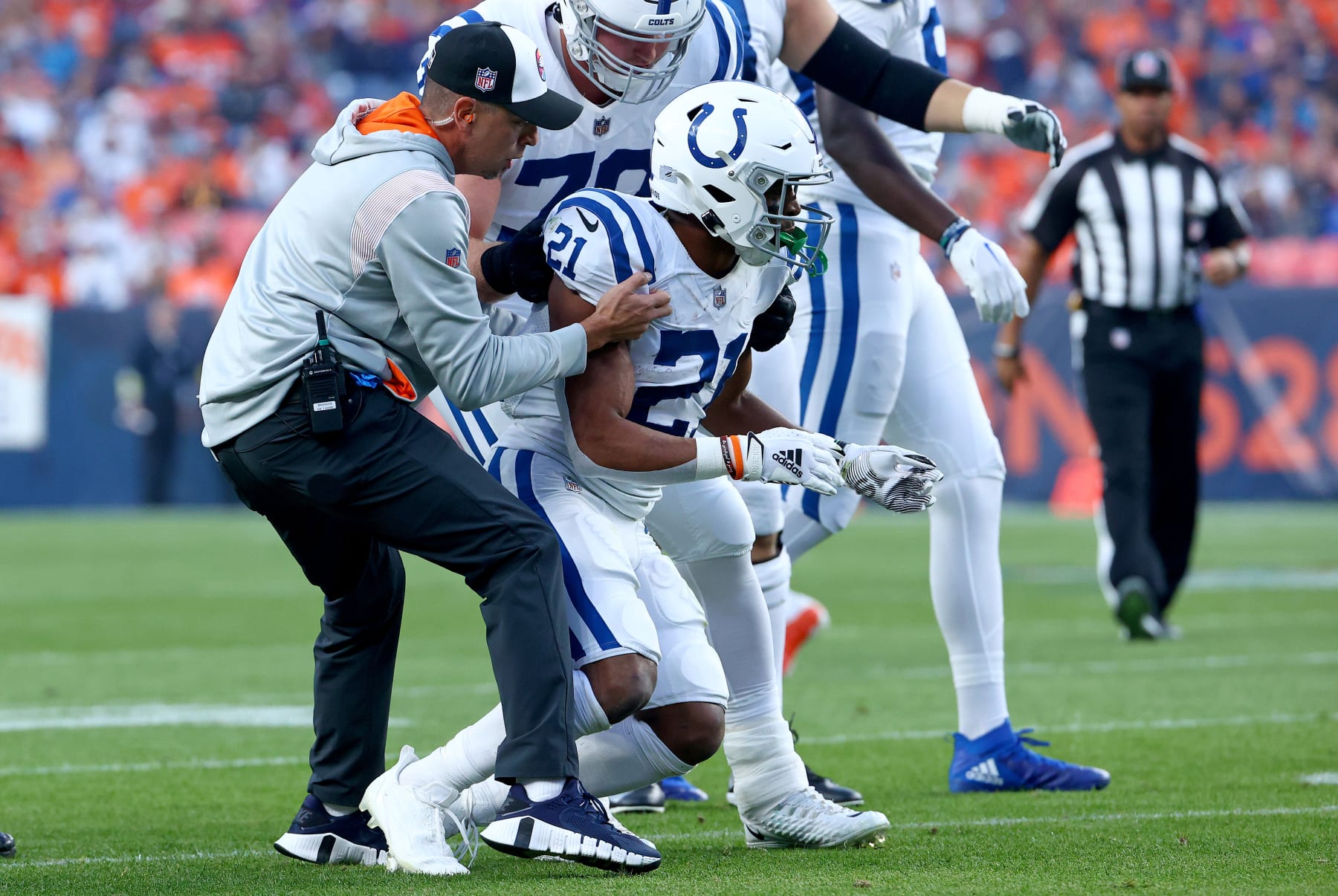 DENVER, COLORADO - OCTOBER 06: Nyheim Hines #21 of the Indianapolis Colts is helped to his feet by #79 after being hit  during a game against the Denver Broncos at Empower Field At Mile High on October 06, 2022 in Denver, Colorado. (Photo by Justin Tafoya/Getty Images)
