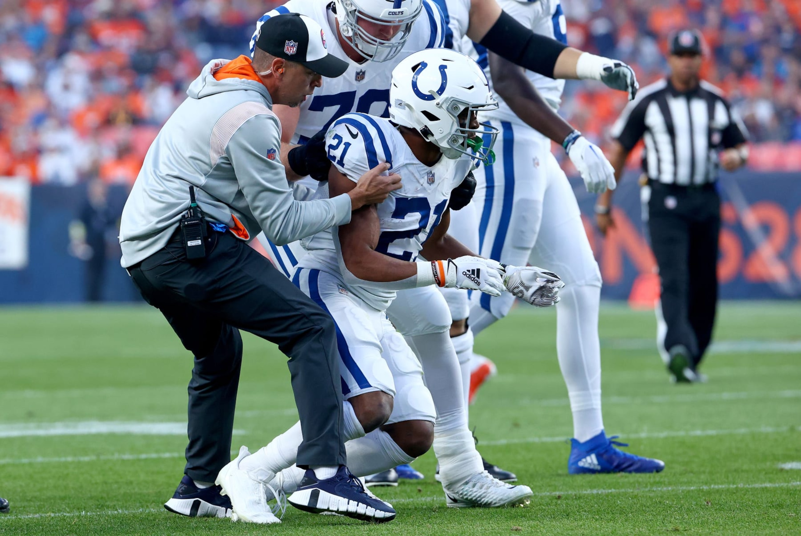 DENVER, COLORADO - OCTOBER 06: Nyheim Hines #21 of the Indianapolis Colts is helped to his feet by #79 after being hit  during a game against the Denver Broncos at Empower Field At Mile High on October 06, 2022 in Denver, Colorado. (Photo by Justin Tafoya/Getty Images)