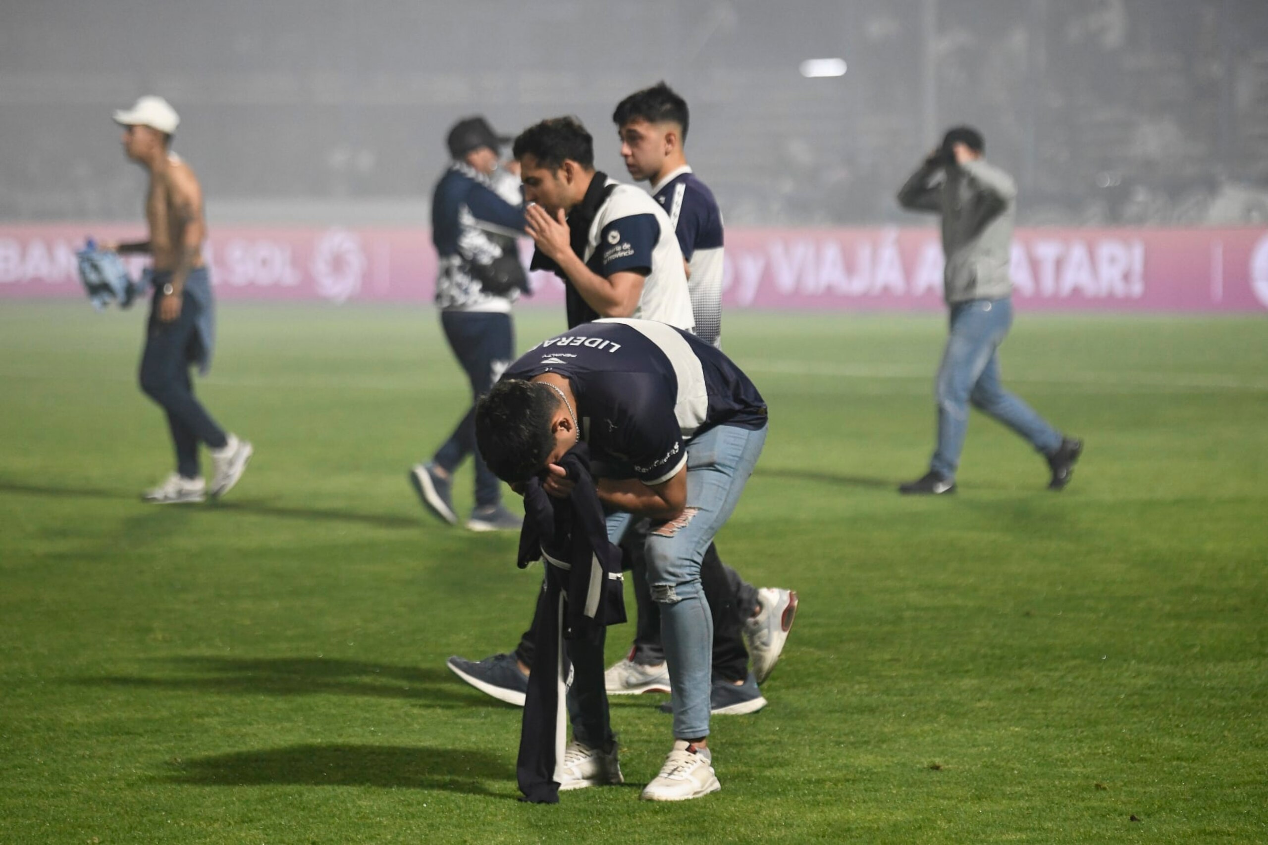 LA PLATA, ARGENTINA - OCTOBER 06: Fans of Gimnasia cover their faces as they are affected by tear gas after a match between Gimnasia y Esgrima La Plata and Boca Juniors was cancelled as part of Liga Profesional 2022 at Juan Carmelo Zerillo Stadium on October 6, 2022 in La Plata, Argentina. The match was stopped at nine minutes of play and later cancelled amid serious incidents outside the stadium with fans and police officers who used tear gas and rubber bullets to disperse the crowd. It was reported a fan of Gimnasia died and many were injured.(Photo by Gustavo Garello/Jam Media/Getty Images) LA PLATA, ARGENTINA - OCTOBER 06: Fans of Gimnasia cover their faces as they are affected by tear gas after a match between Gimnasia y Esgrima La Plata and Boca Juniors was cancelled as part of Liga Profesional 2022 at Juan Carmelo Zerillo Stadium on October 6, 2022 in La Plata, Argentina. The match was stopped at nine minutes of play and later cancelled amid serious incidents outside the stadium with fans and police officers who used tear gas and rubber bullets to disperse the crowd. It was reported a fan of Gimnasia died and many were injured.(Photo by Gustavo Garello/Jam Media/Getty Images)