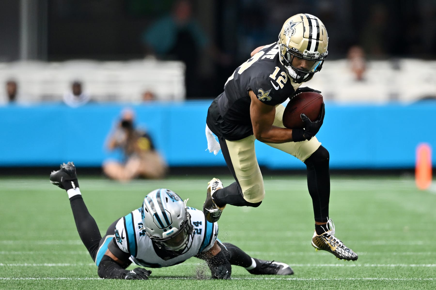 CHARLOTTE, NORTH CAROLINA - SEPTEMBER 25: Chris Olave #12 of the New Orleans Saints runs with the ball against CJ Henderson #24 of the Carolina Panthers during the third quarter at Bank of America Stadium on September 25, 2022 in Charlotte, North Carolina. (Photo by Grant Halverson/Getty Images)