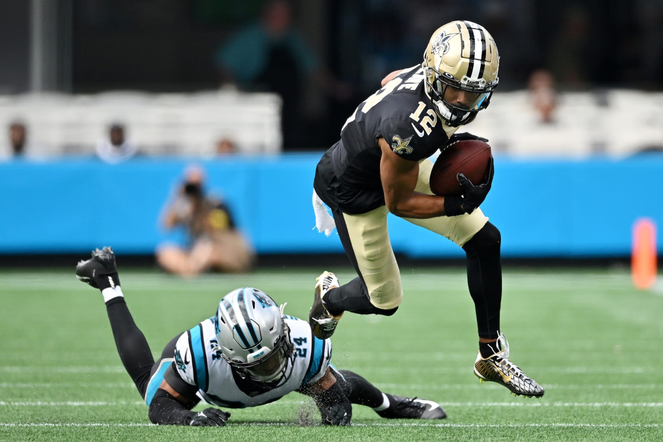 CHARLOTTE, NORTH CAROLINA - SEPTEMBER 25: Chris Olave #12 of the New Orleans Saints runs with the ball against CJ Henderson #24 of the Carolina Panthers during the third quarter at Bank of America Stadium on September 25, 2022 in Charlotte, North Carolina. (Photo by Grant Halverson/Getty Images)
