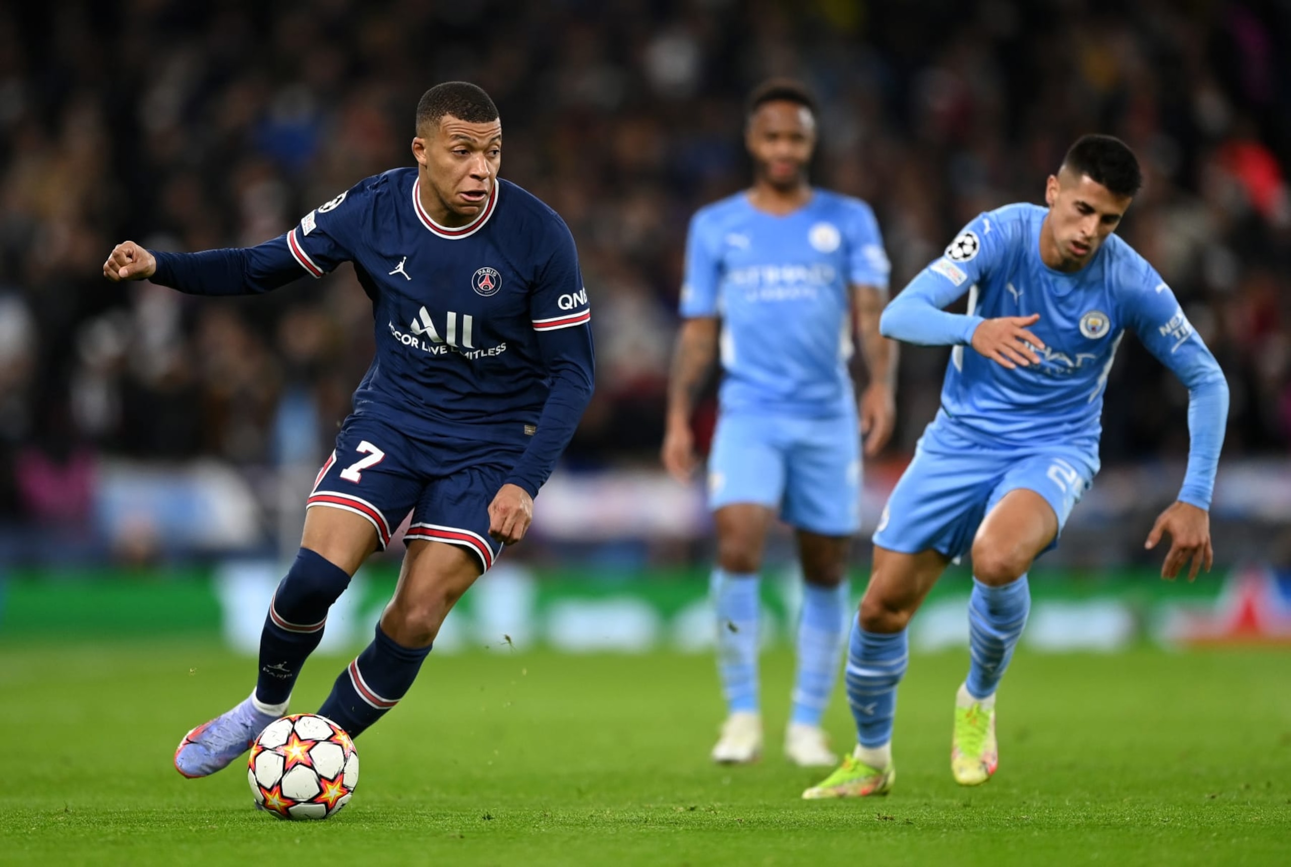 MANCHESTER, ENGLAND - NOVEMBER 24:  Kylian Mbappe of Paris Saint-Germain breaks away from Joao Cancelo of Manchester City during the UEFA Champions League group A match between Manchester City and Paris Saint-Germain at Etihad Stadium on November 24, 2021 in Manchester, England. (Photo by Shaun Botterill/Getty Images)