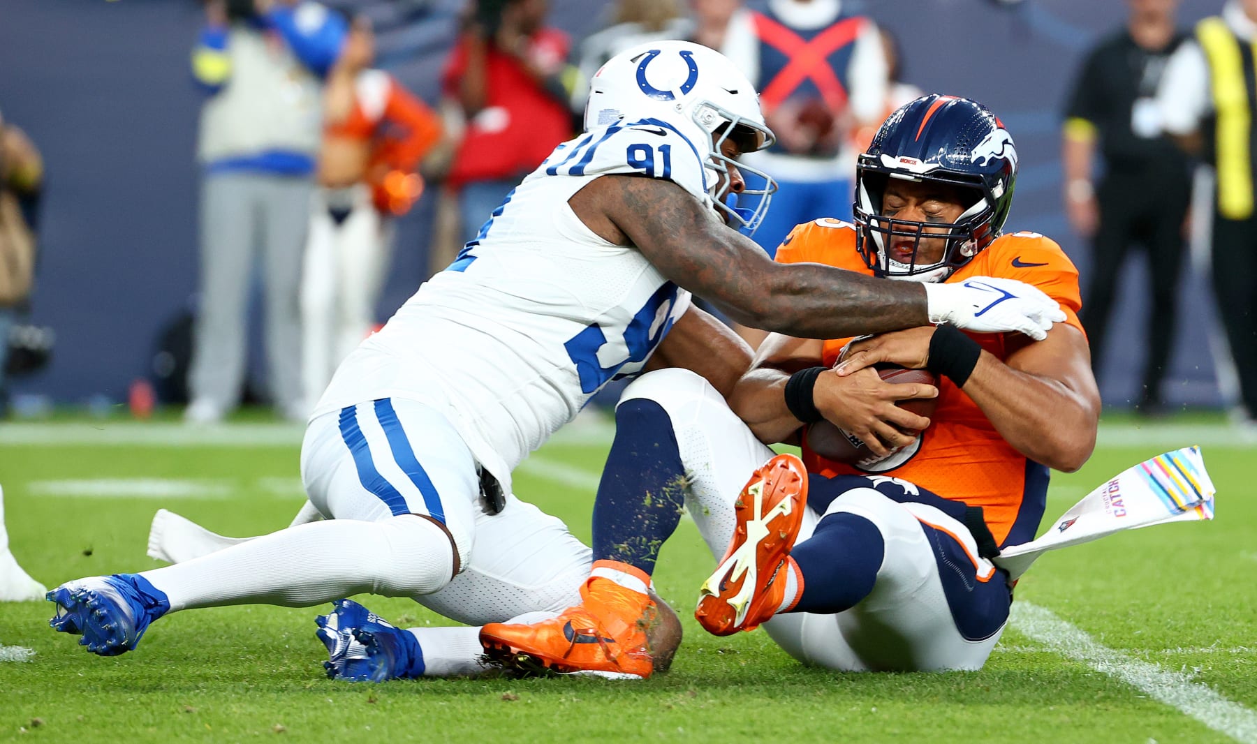 DENVER, COLORADO - OCTOBER 06: Russell Wilson #3 of the Denver Broncos is sacked by Yannick Ngakoue #91 of the Indianapolis Colts during a game  at Empower Field At Mile High on October 06, 2022 in Denver, Colorado. (Photo by Justin Tafoya/Getty Images)