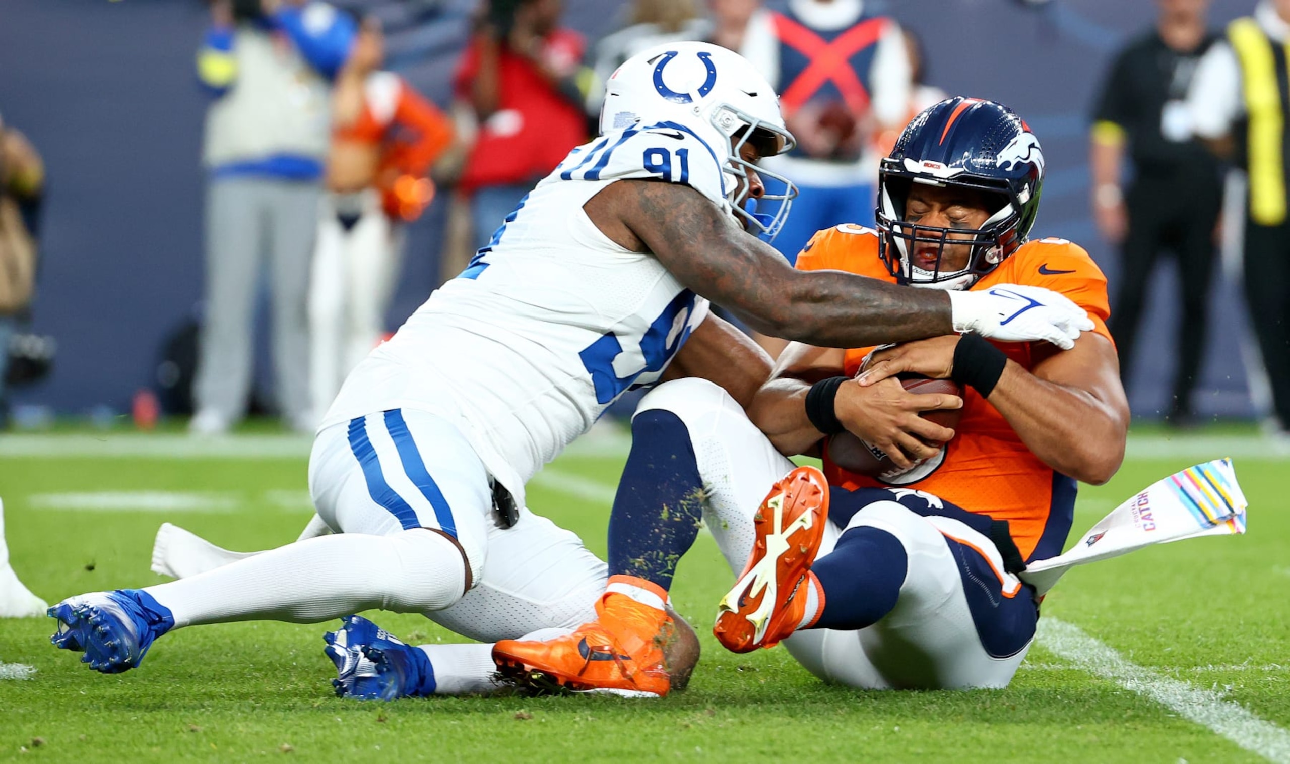 DENVER, COLORADO - OCTOBER 06: Russell Wilson #3 of the Denver Broncos is sacked by Yannick Ngakoue #91 of the Indianapolis Colts during a game  at Empower Field At Mile High on October 06, 2022 in Denver, Colorado. (Photo by Justin Tafoya/Getty Images)