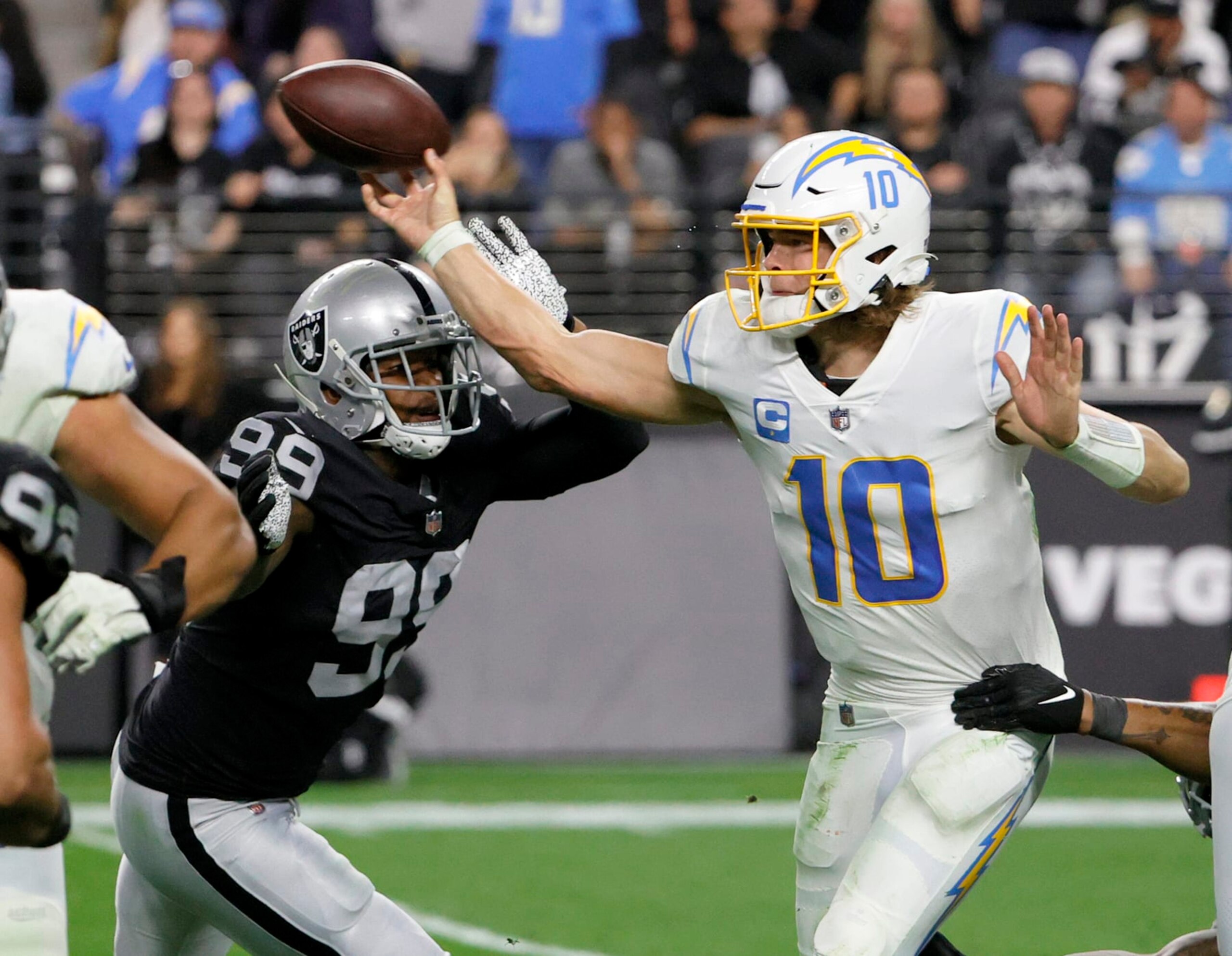 LAS VEGAS, NEVADA - JANUARY 09:  Quarterback Justin Herbert #10 of the Los Angeles Chargers throws under pressure from defensive end Clelin Ferrell #99 of the Las Vegas Raiders during their game at Allegiant Stadium on January 9, 2022 in Las Vegas, Nevada. The Raiders defeated the Chargers 35-32 in overtime.  (Photo by Ethan Miller/Getty Images)