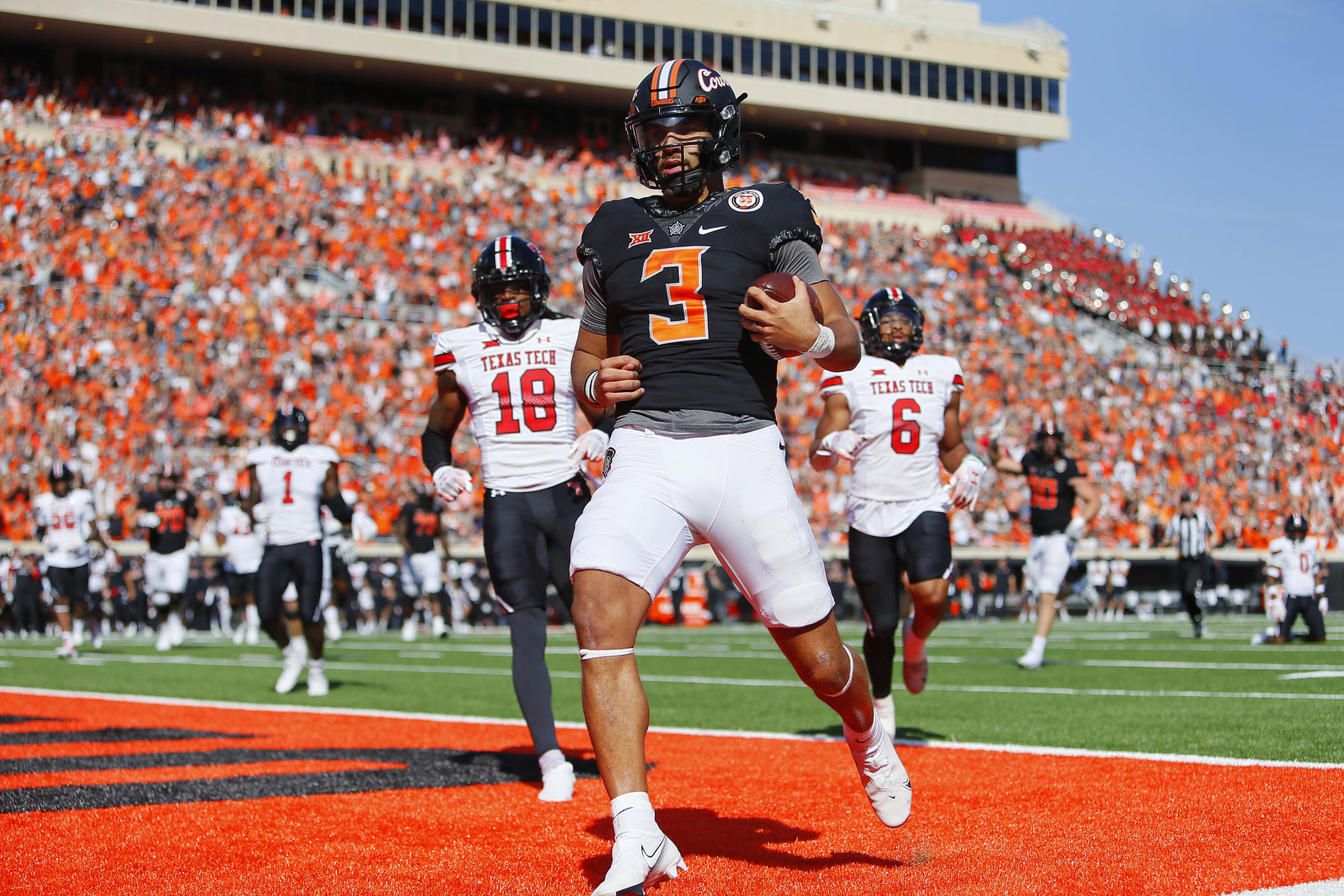 STILLWATER, OK - OCTOBER 8:  Quarterback Spencer Sanders #3 of the Oklahoma State Cowboys scores a touchdown on a 14-yard run against defensive back Tyler Owens #18 and linebacker Kosi Eldridge #6 of the Texas Tech Red Raiders in the first quarter at Boone Pickens Stadium on October 8, 2022 in Stillwater, Oklahoma.  Oklahoma State won 41-31.  (Photo by Brian Bahr/Getty Images)