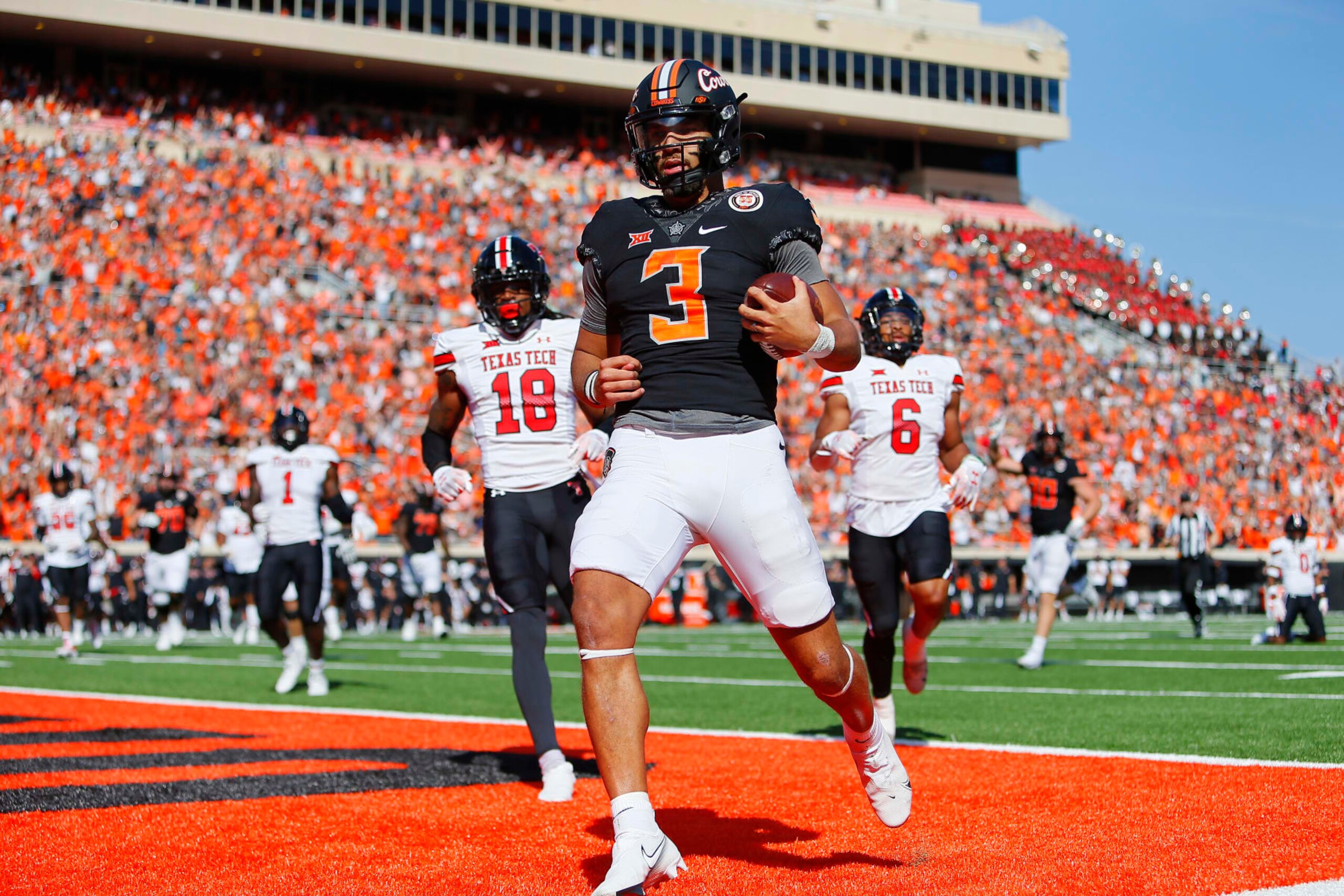 STILLWATER, OK - OCTOBER 8:  Quarterback Spencer Sanders #3 of the Oklahoma State Cowboys scores a touchdown on a 14-yard run against defensive back Tyler Owens #18 and linebacker Kosi Eldridge #6 of the Texas Tech Red Raiders in the first quarter at Boone Pickens Stadium on October 8, 2022 in Stillwater, Oklahoma.  Oklahoma State won 41-31.  (Photo by Brian Bahr/Getty Images)