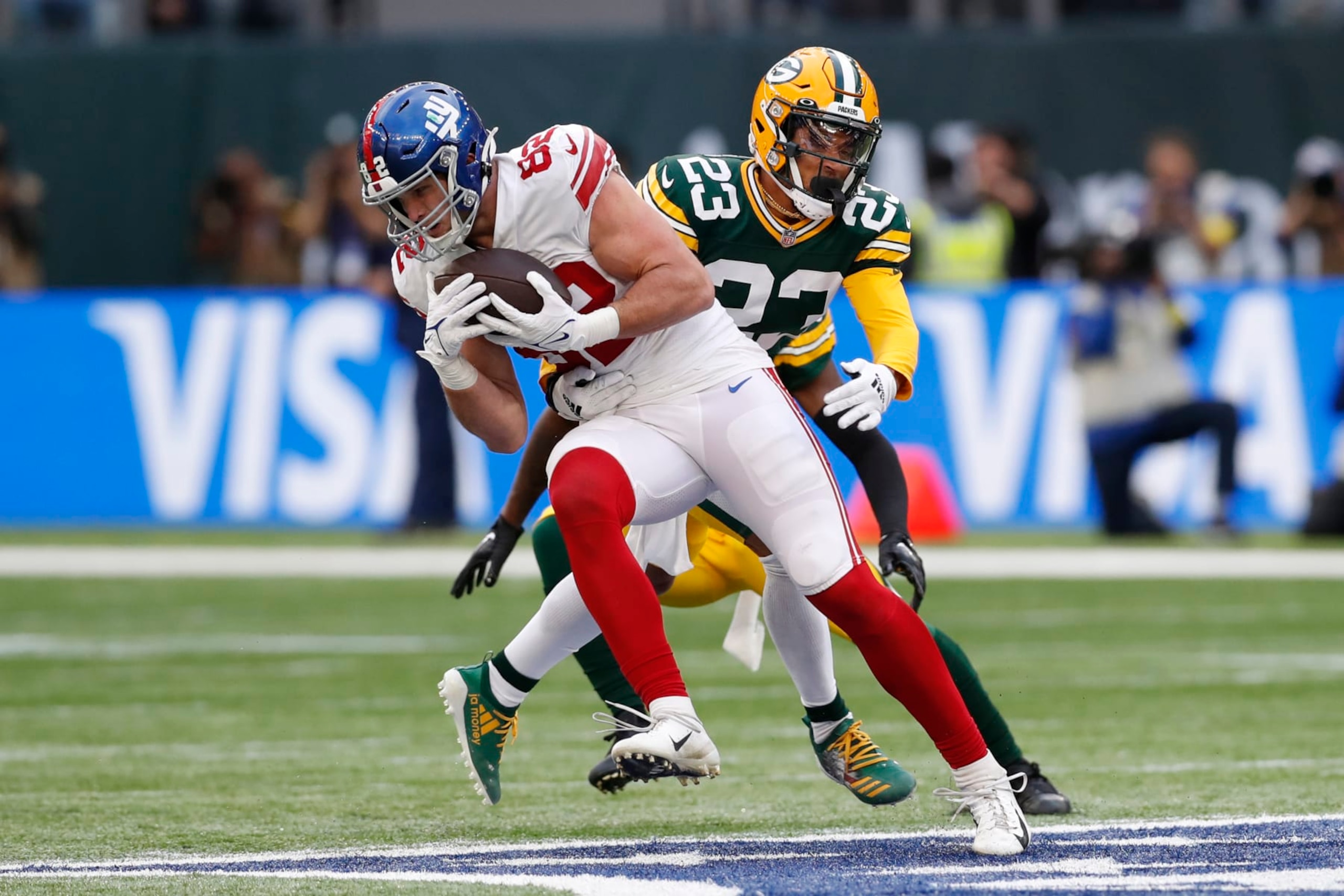 Green Bay Packers cornerback Jaire Alexander (23) tackles New York Giants tight end Daniel Bellinger (82) during an NFL football game at Tottenham Hotspur Stadium in London, Sunday, Oct. 9, 2022. The New York Giants won 27-22. (AP Photo/Steve Luciano)