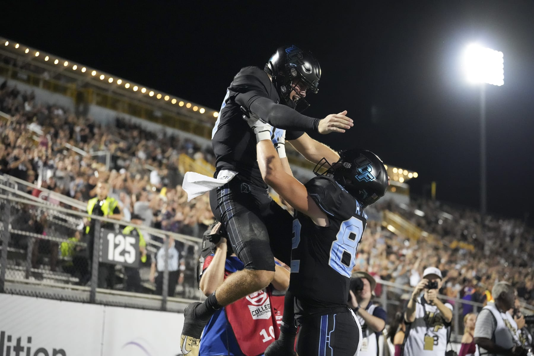 ORLANDO, FL - OCTOBER 13: UCF Knights quarterback John Rhys Plumlee (10) gets lifted up by UCF Knights tight end Alec Holler (82) after his touchdown run during the game between the Temple Owls and the University of Central Florida (UCF) Knights on Thursday, October 13, 2022 at Bright House Networks Stadium in Orlando, FL (Photo by Peter Joneleit/Icon Sportswire via Getty Images)