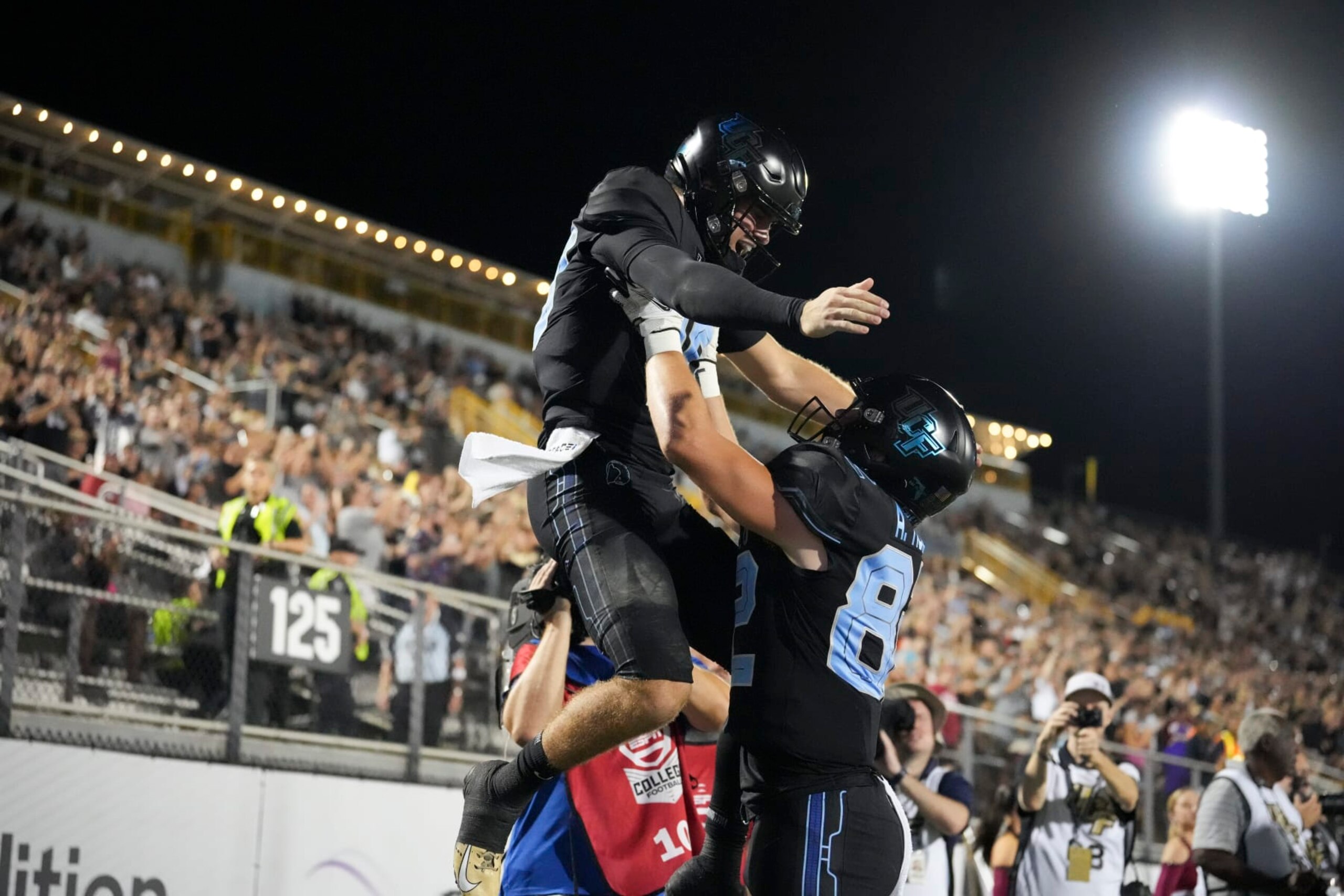 ORLANDO, FL - OCTOBER 13: UCF Knights quarterback John Rhys Plumlee (10) gets lifted up by UCF Knights tight end Alec Holler (82) after his touchdown run during the game between the Temple Owls and the University of Central Florida (UCF) Knights on Thursday, October 13, 2022 at Bright House Networks Stadium in Orlando, FL (Photo by Peter Joneleit/Icon Sportswire via Getty Images)