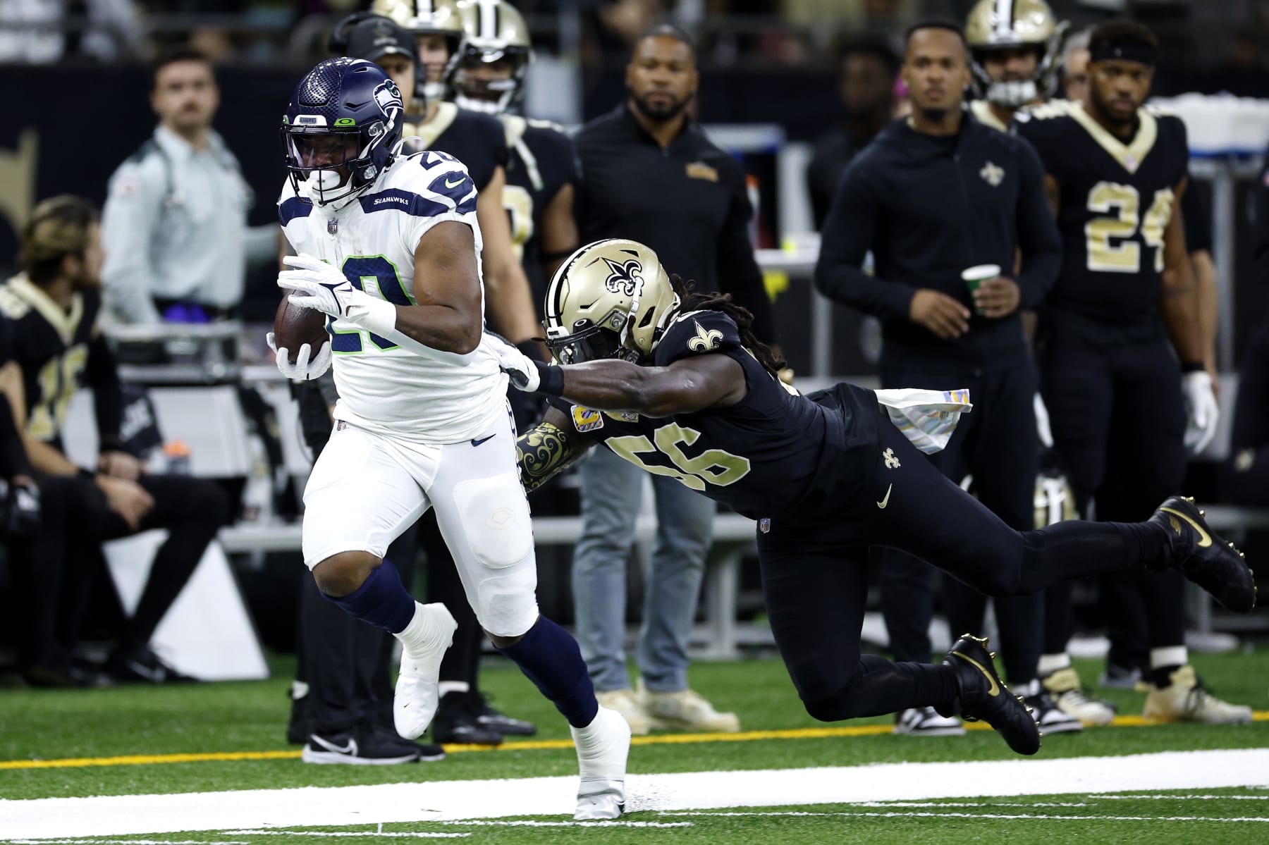 NEW ORLEANS, LOUISIANA - OCTOBER 09: Rashaad Penny #20 of the Seattle Seahawks runs the ball in front of Demario Davis #56 of the New Orleans Saints during the first quarter at Caesars Superdome on October 09, 2022 in New Orleans, Louisiana. (Photo by Chris Graythen/Getty Images)