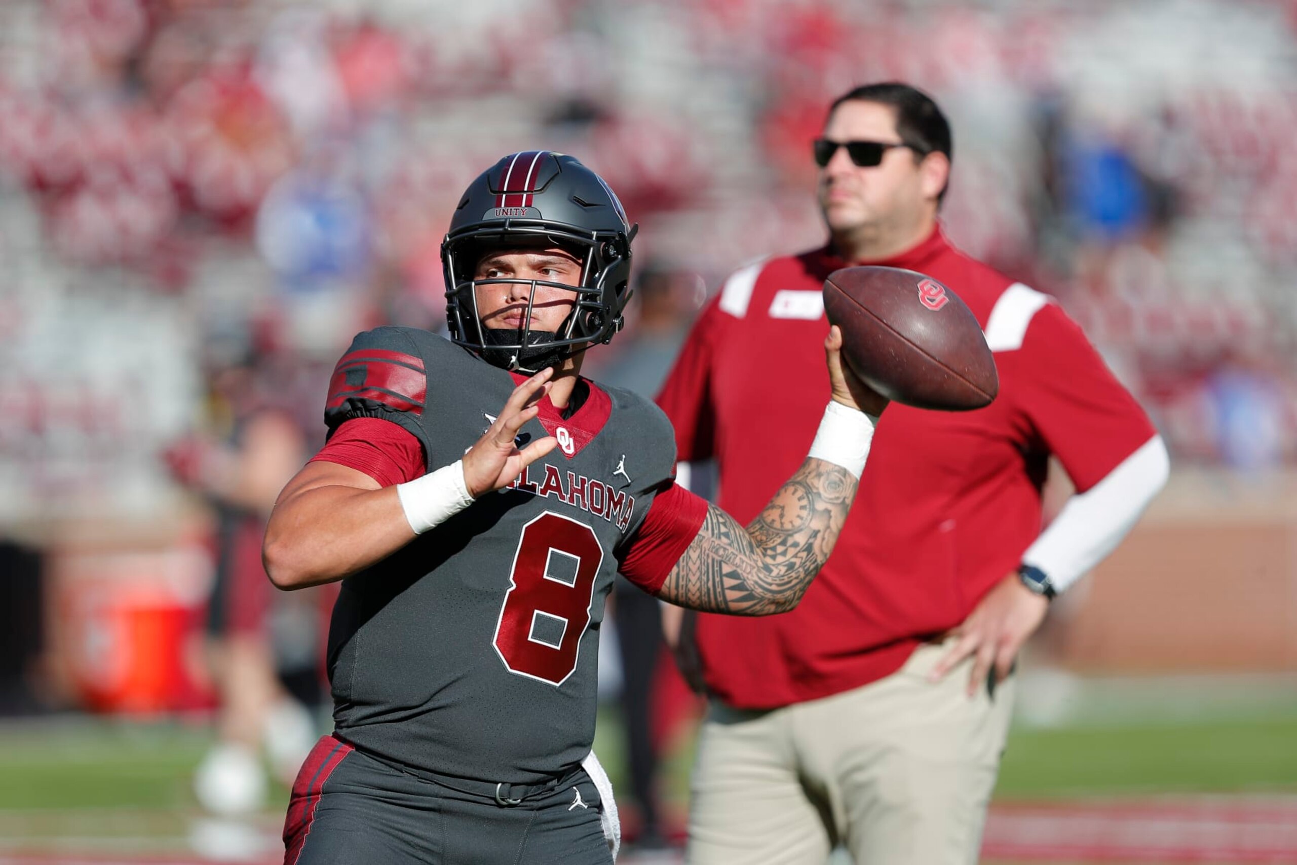 Oklahoma quarterback Dillon Gabriel (8) warms up as offensive coordinator Jeff Lebby watches from the background before the start of an NCAA college football game against Kansas on Saturday, Oct. 15, 2022, in Norman, Okla. (AP Photo/Alonzo Adams)