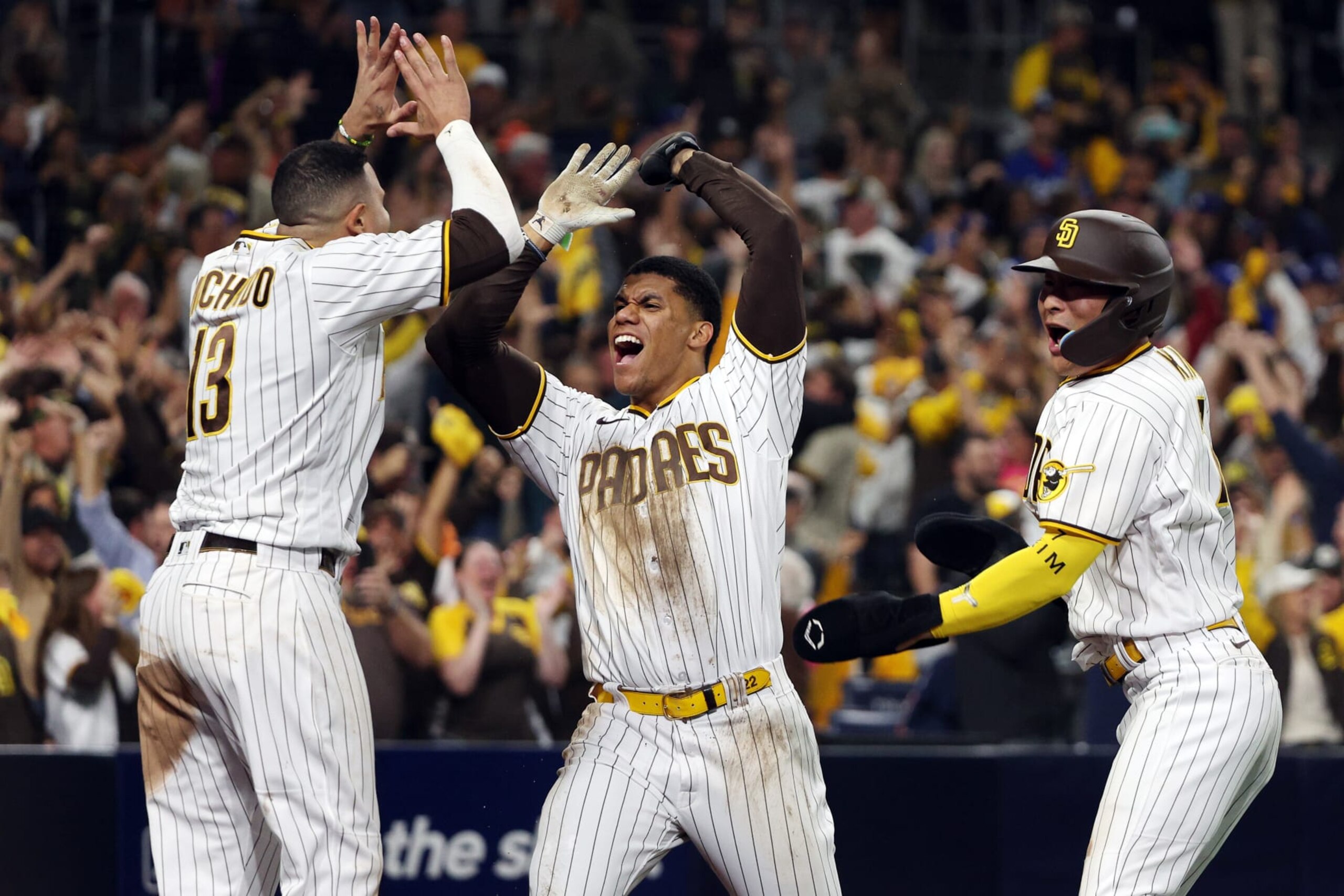 SAN DIEGO, CALIFORNIA - OCTOBER 15: Juan Soto #22 and Ha-Seong Kim #7 celebrate with Manny Machado #13 of the San Diego Padres after scoring two runs during the seventh inning to go up 5-3 against the Los Angeles Dodgers in game four of the National League Division Series at PETCO Park on October 15, 2022 in San Diego, California. (Photo by Harry How/Getty Images)