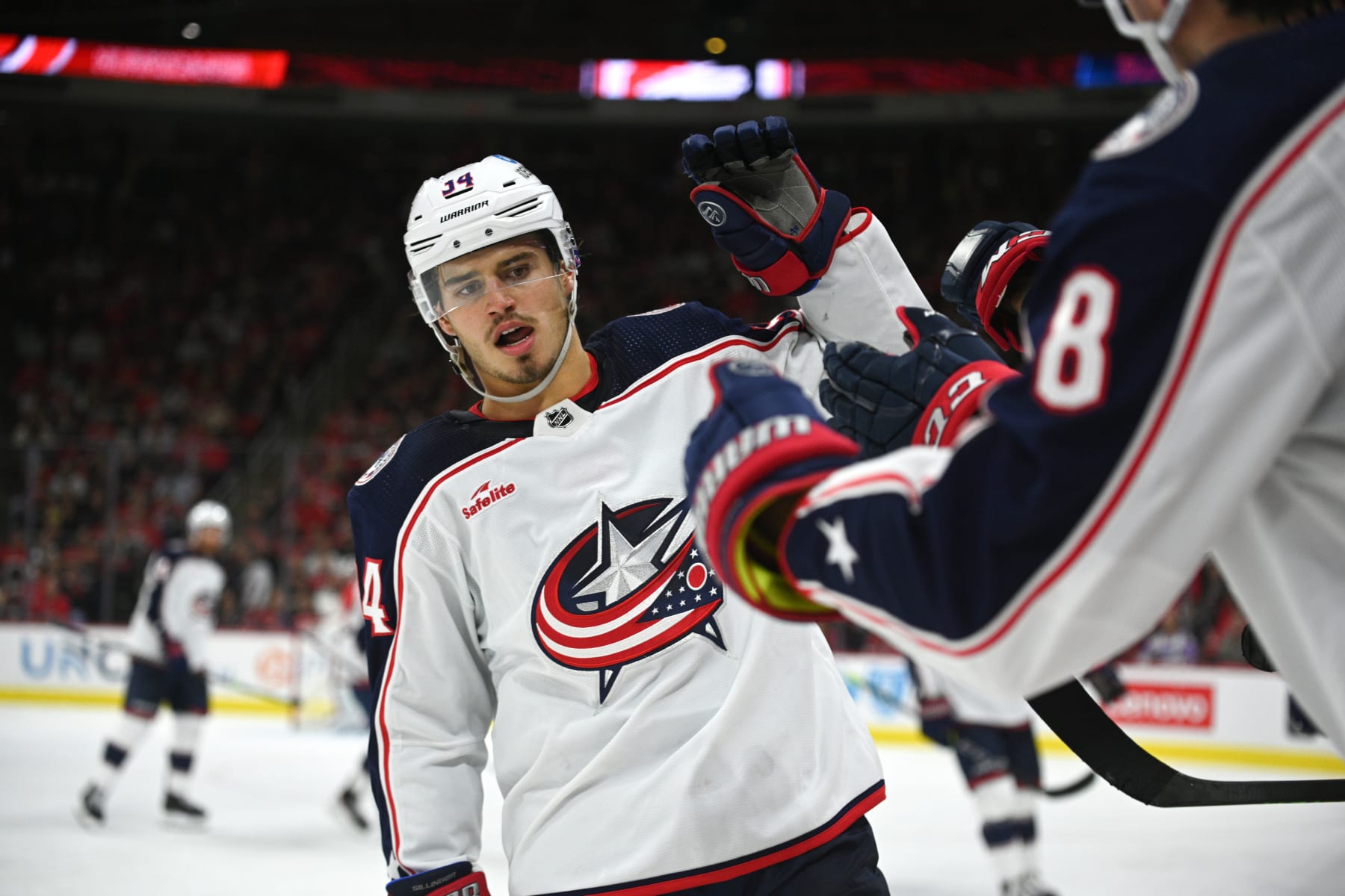 RALEIGH, NORTH CAROLINA - OCTOBER 12: Cole Sillinger #34 of the Columbus Blue Jackets high-fives teammates to celebrate scoring a goal, prior to the goal being overturned during the game against the Carolina Hurricanes at PNC Arena on October 12, 2022 in Raleigh, North Carolina. (Photo by Kaydee Gawlik/NHLI via Getty Images)