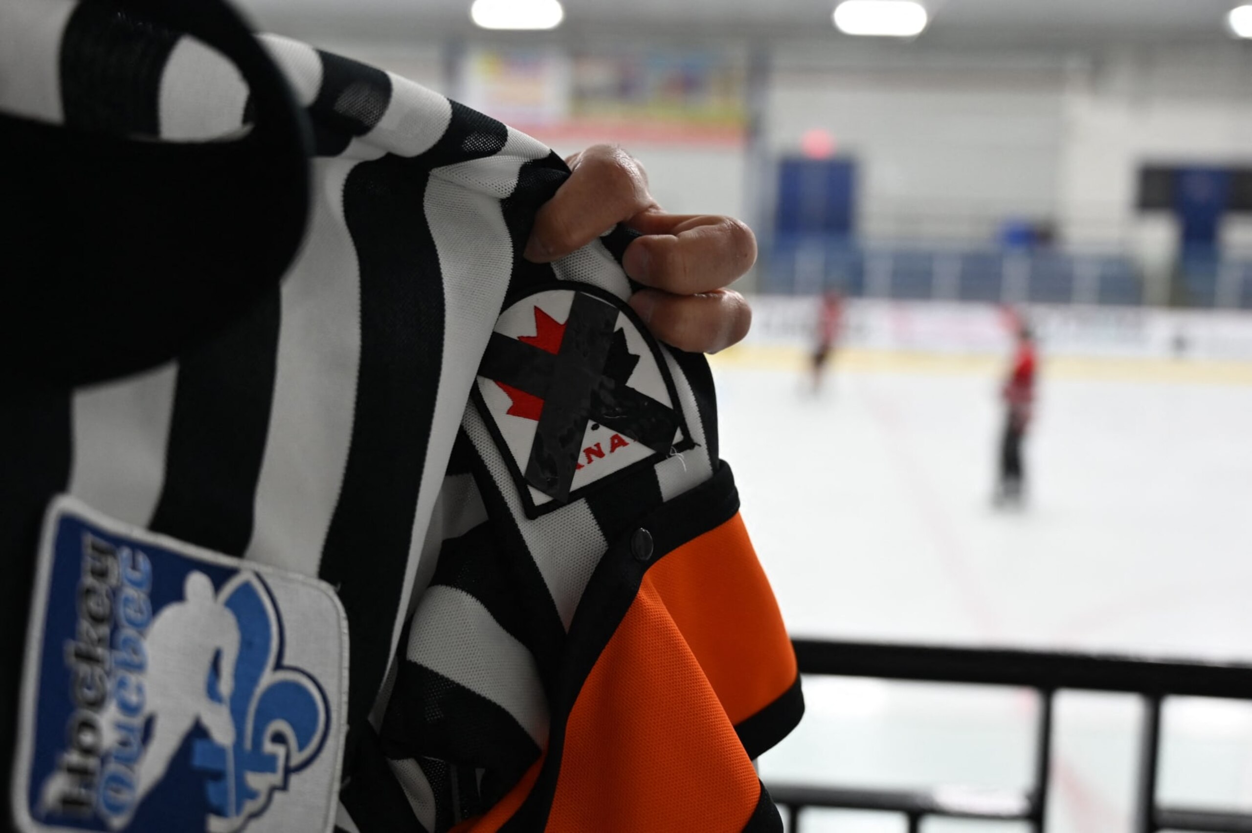 Referee Martin Pronovost wears a Hockey Canada patch crossed with black ribbon during an ice hockey game at Arena La Plaine in Montreal on June 10, 2022, to generate discussion and raise awareness as the hockey federation faces a sexual assault scandal. - True Canadian pride, ice hockey and especially its national federation are living dark hours in recent weeks, tarnished by a case of gang rape that resurfaces a culture of silence too long ignored. In May, Canadians were shocked to learn that eight players on the 2018 Junior National Team had been charged with gang sexual assault of a young woman. It was even more of a surprise when they learned that the organization supposedly overseeing them had allegedly tried to cover up the case by entering into a confidential multi-million dollar settlement with the victim. (Photo by Mathiew LEISER / AFP) (Photo by MATHIEW LEISER/AFP via Getty Images)