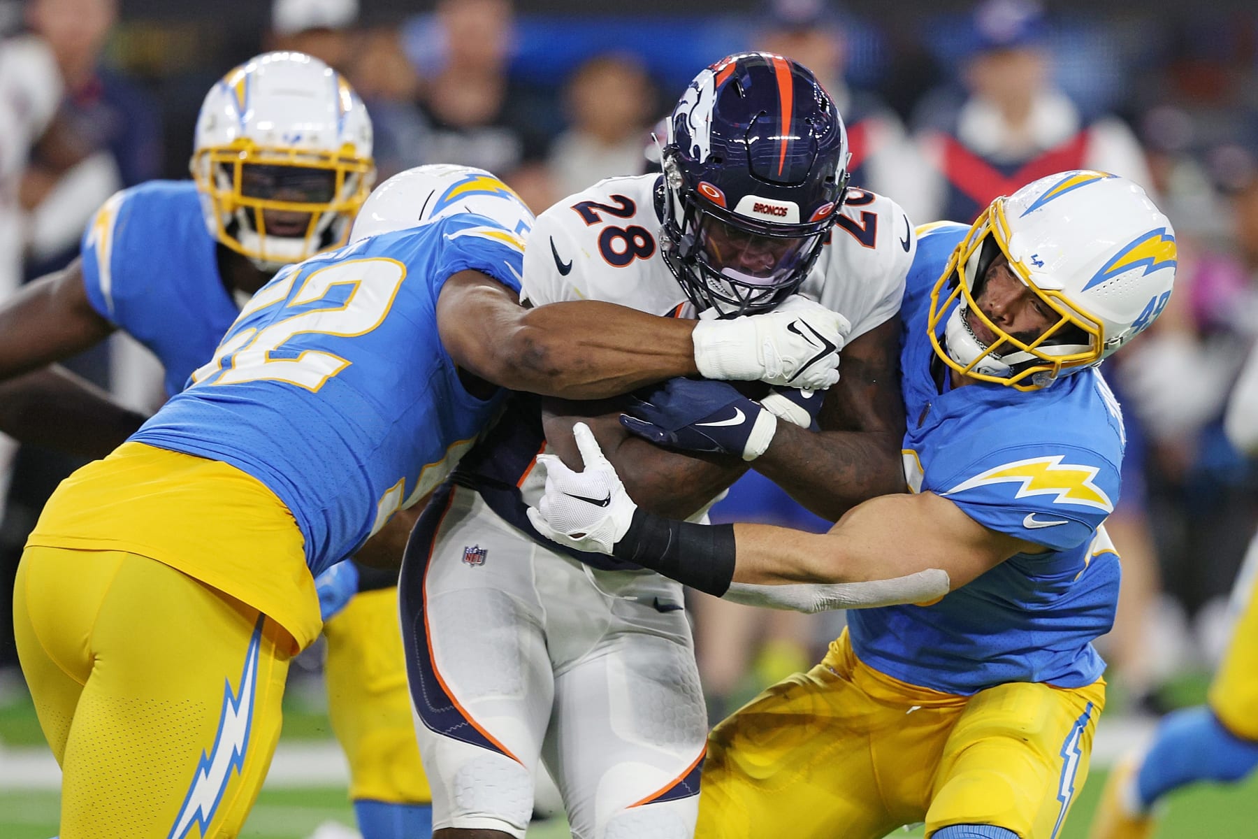 INGLEWOOD, CALIFORNIA - OCTOBER 17: Latavius Murray #28 of the Denver Broncos is brought down by Khalil Mack #52 and Drue Tranquill #49 of the Los Angeles Chargers during the third quarter at SoFi Stadium on October 17, 2022 in Inglewood, California. (Photo by Harry How/Getty Images)