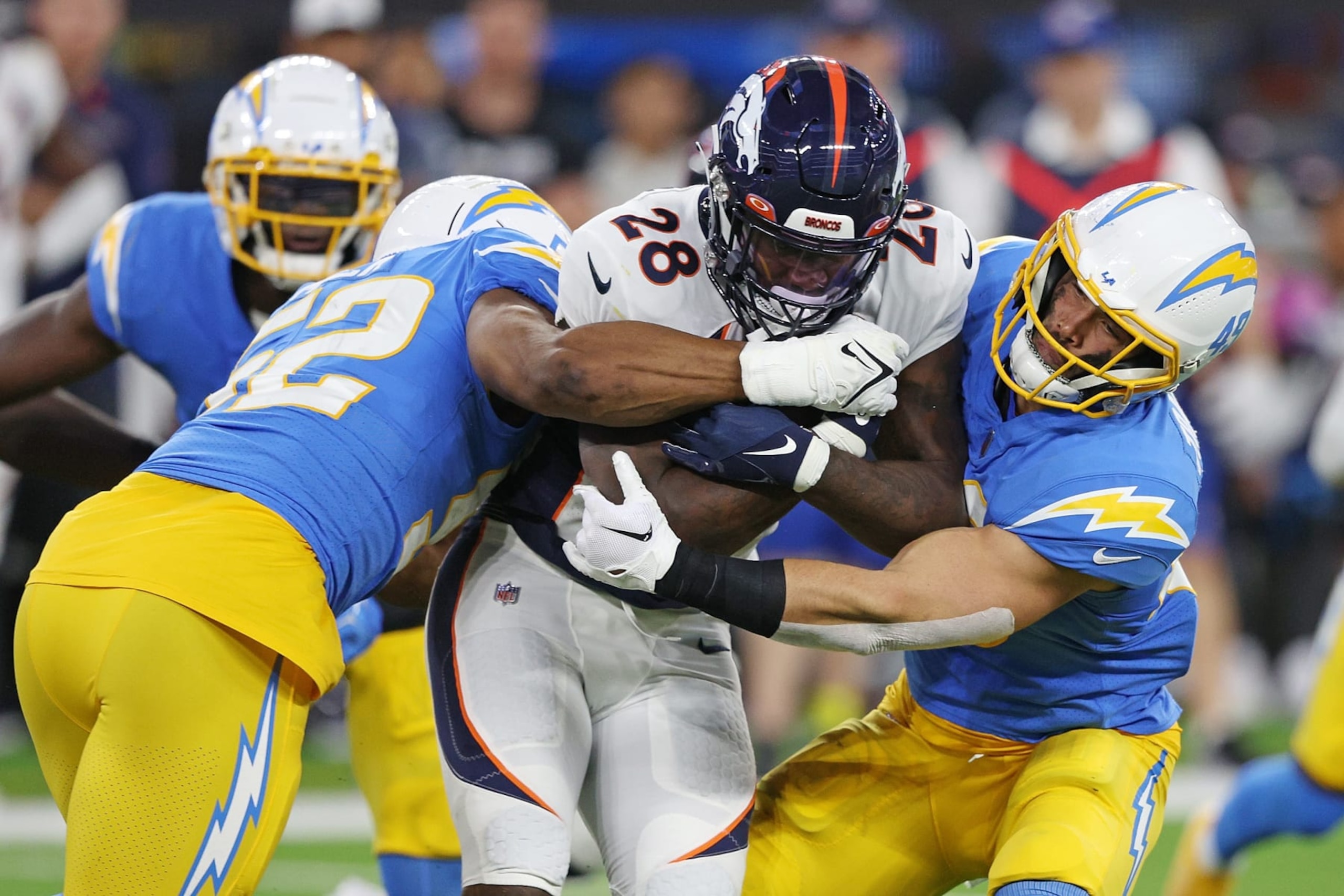 INGLEWOOD, CALIFORNIA - OCTOBER 17: Latavius Murray #28 of the Denver Broncos is brought down by Khalil Mack #52 and Drue Tranquill #49 of the Los Angeles Chargers during the third quarter at SoFi Stadium on October 17, 2022 in Inglewood, California. (Photo by Harry How/Getty Images)