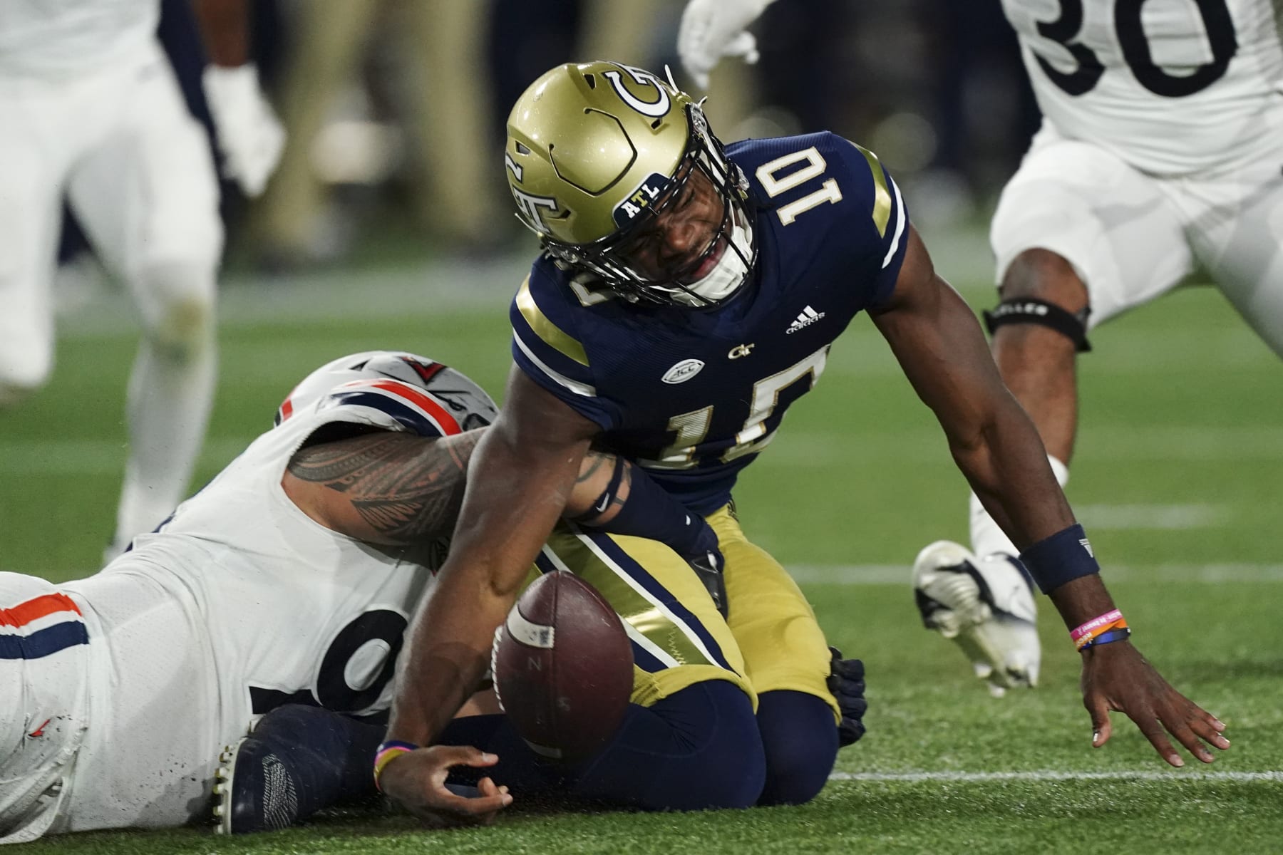 Georgia Tech quarterback Jeff Sims (10) loses the ball as he is tackled by Virginia defensive lineman Aaron Faumui (94) during the first half of an NCAA college football game Thursday, Oct. 20, 2022, in Atlanta. After review, Sims was ruled down before losing the ball. (AP Photo/John Bazemore)