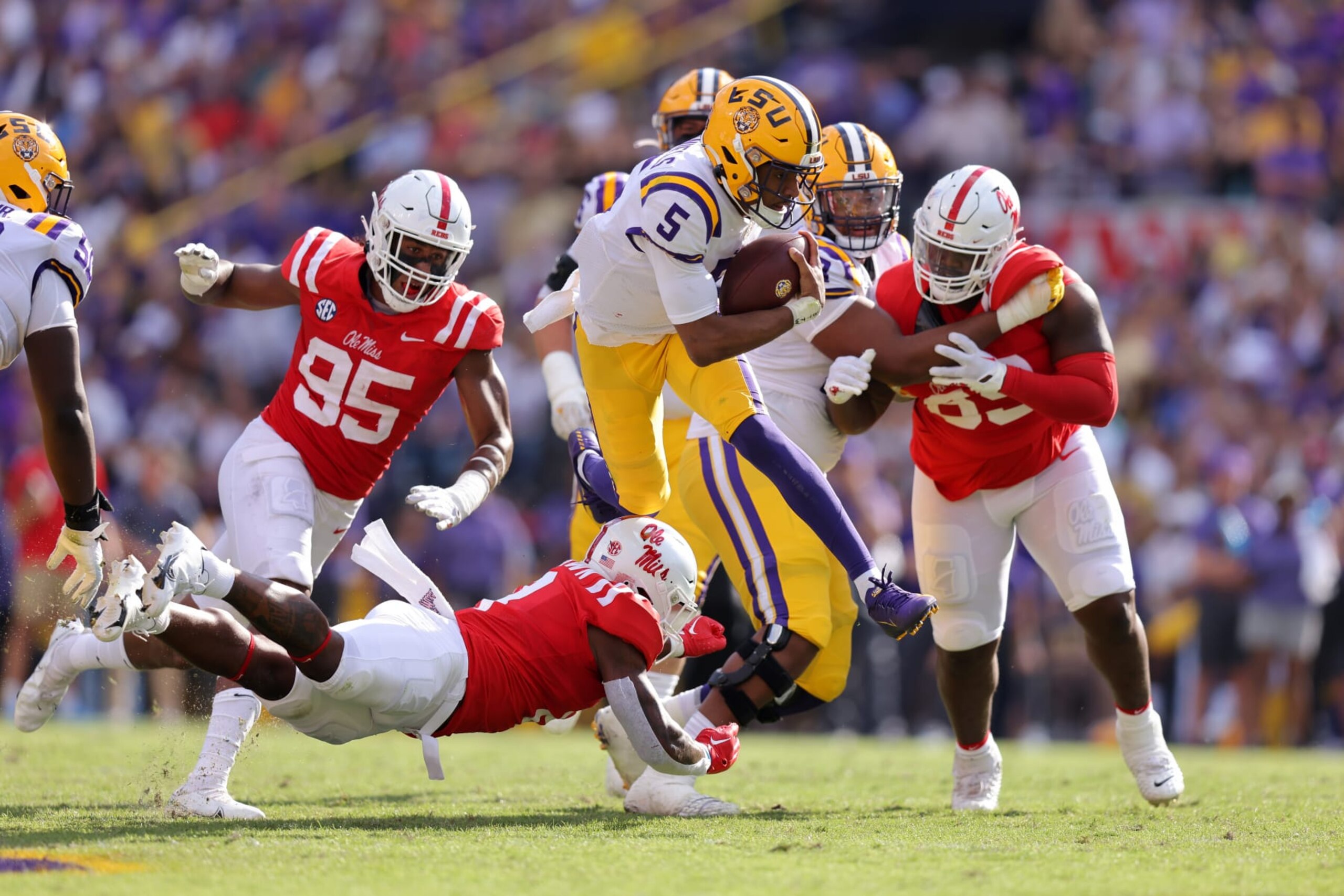 BATON ROUGE, LOUISIANA - OCTOBER 22: Jayden Daniels #5 of the LSU Tigers hurdles over Markevious Brown #28 of the Mississippi Rebels during the first half at Tiger Stadium on October 22, 2022 in Baton Rouge, Louisiana. (Photo by Jonathan Bachman/Getty Images)