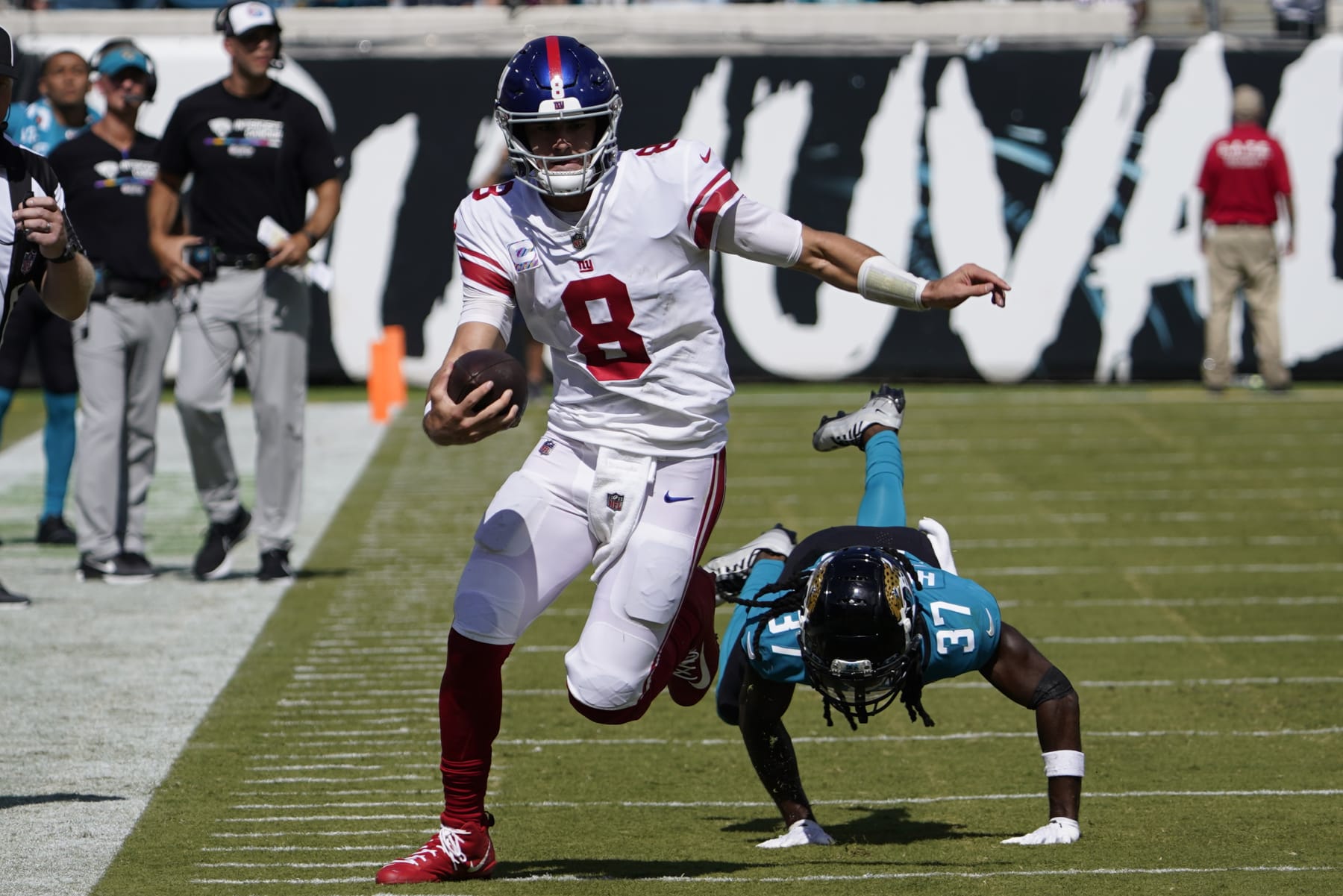 New York Giants quarterback Daniel Jones (8) scrambles away from Jacksonville Jaguars cornerback Tre Herndon (37) during the first half of an NFL football game Sunday, Oct. 23, 2022, in Jacksonville, Fla. (AP Photo/John Raoux)