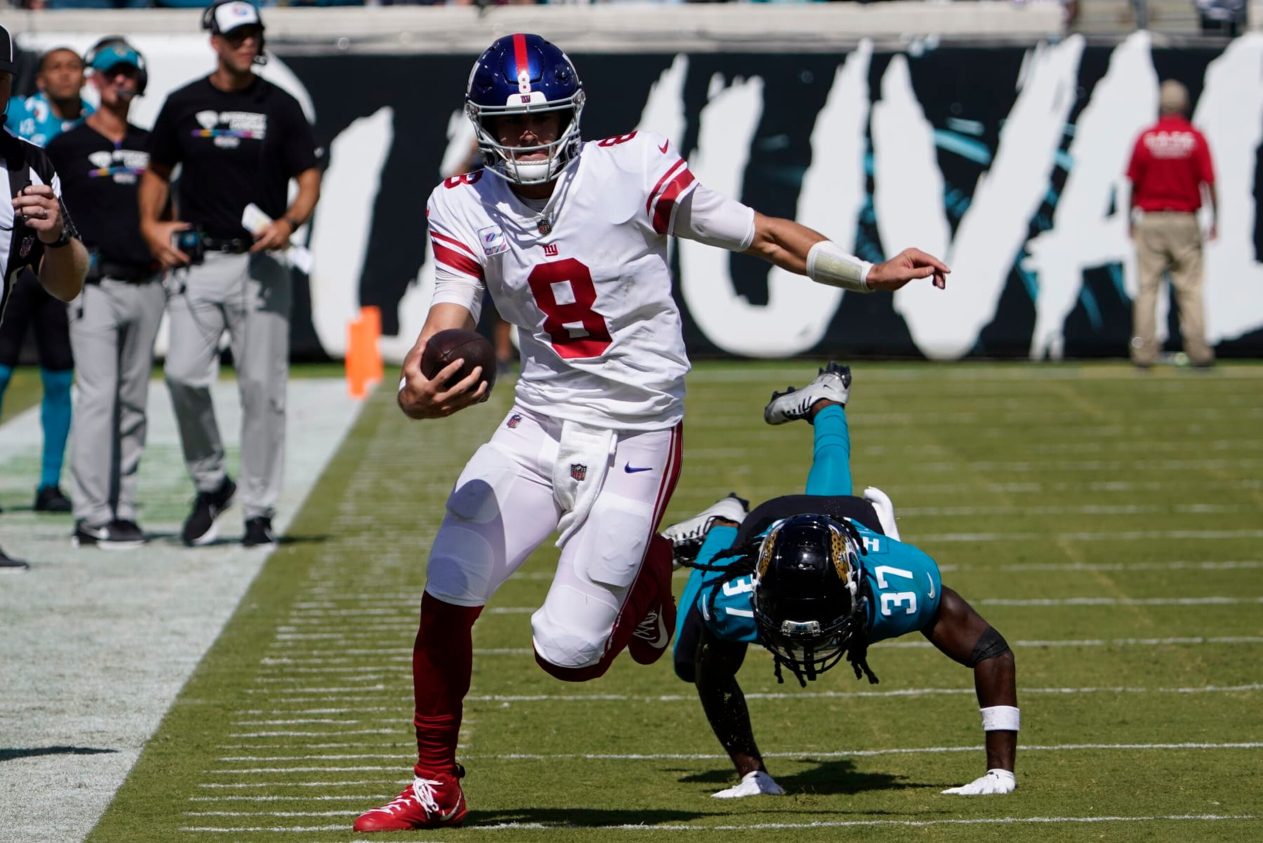 New York Giants quarterback Daniel Jones (8) scrambles away from Jacksonville Jaguars cornerback Tre Herndon (37) during the first half of an NFL football game Sunday, Oct. 23, 2022, in Jacksonville, Fla. (AP Photo/John Raoux)