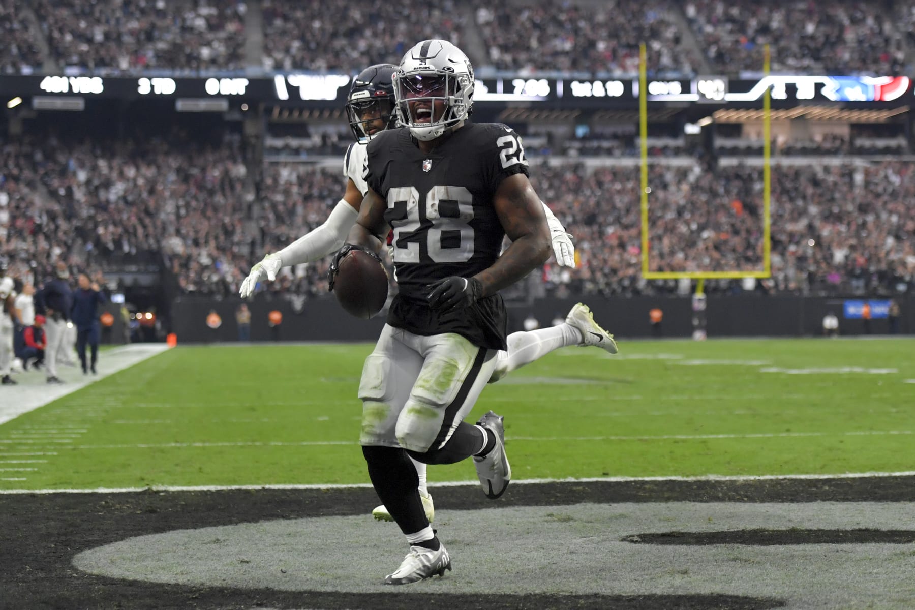 Las Vegas Raiders running back Josh Jacobs, left, scores a touchdown as Houston Texans safety Jonathan Owens defends during the second half of an NFL football game Sunday, Oct. 23, 2022, in Las Vegas. (AP Photo/David Becker)
