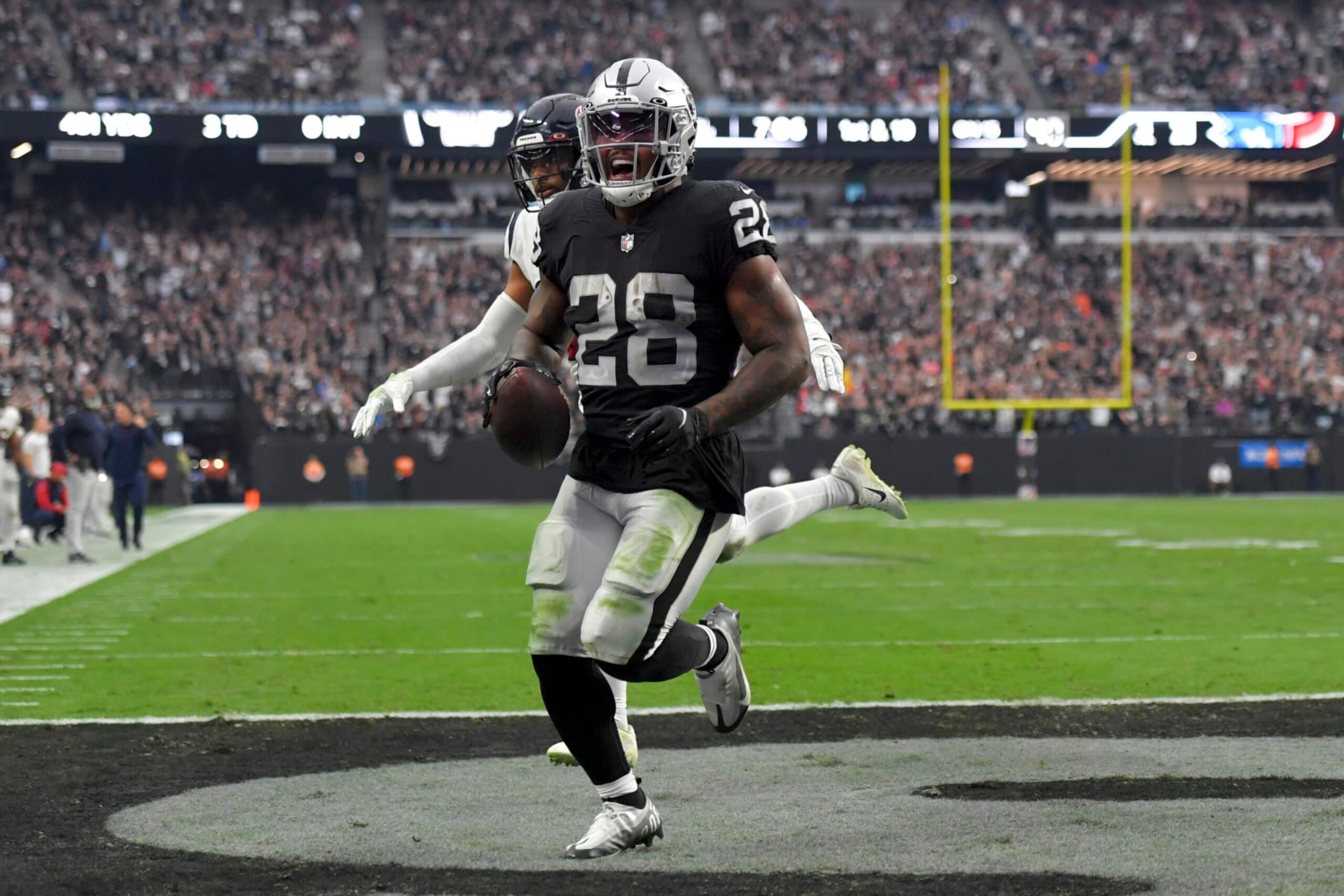 Las Vegas Raiders running back Josh Jacobs, left, scores a touchdown as Houston Texans safety Jonathan Owens defends during the second half of an NFL football game Sunday, Oct. 23, 2022, in Las Vegas. (AP Photo/David Becker)