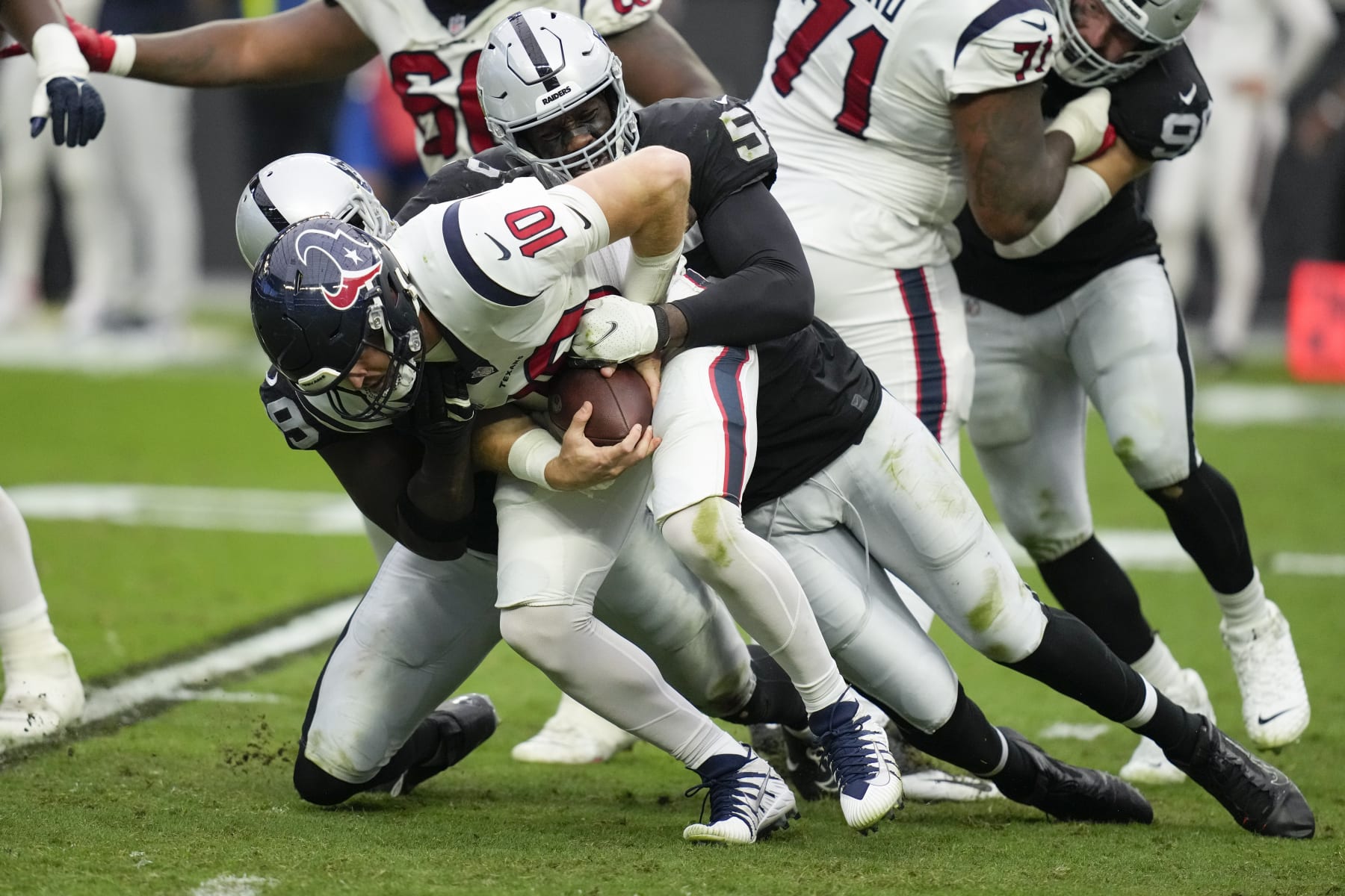 Houston Texans quarterback Davis Mills is brought down for a sack by Las Vegas Raiders defensive end Clelin Ferrell, left, and defensive end Chandler Jones during the first half of an NFL football game Sunday, Oct. 23, 2022, in Las Vegas. (AP Photo/John Locher)