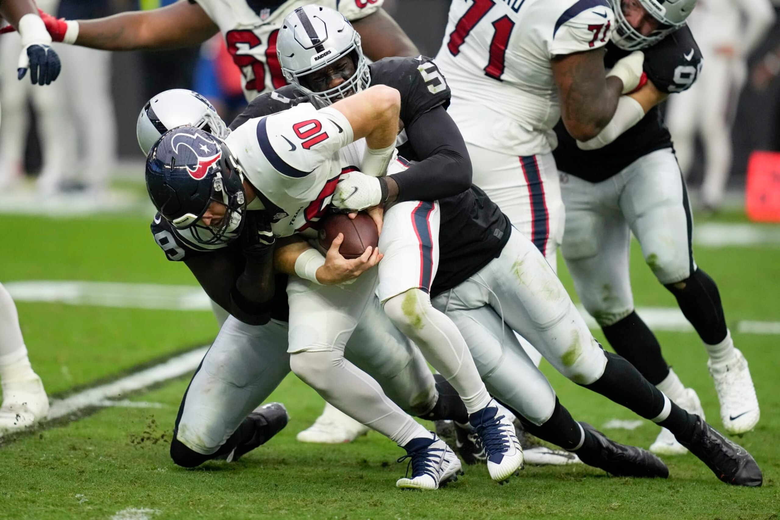 Houston Texans quarterback Davis Mills is brought down for a sack by Las Vegas Raiders defensive end Clelin Ferrell, left, and defensive end Chandler Jones during the first half of an NFL football game Sunday, Oct. 23, 2022, in Las Vegas. (AP Photo/John Locher)