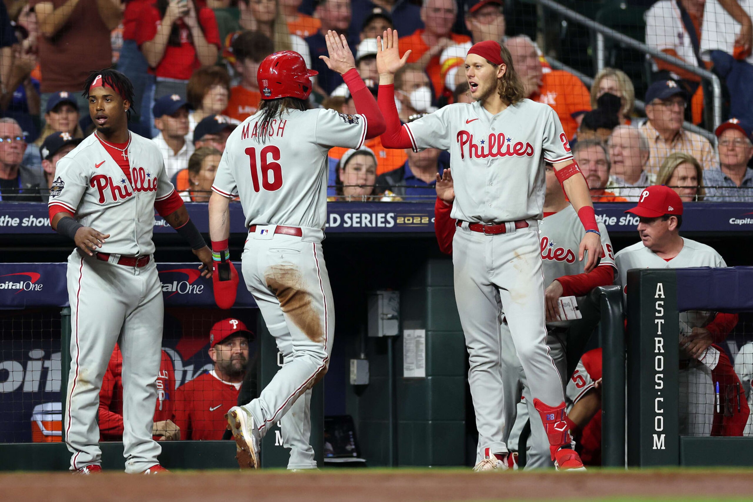 HOUSTON, TEXAS - OCTOBER 28: Jean Segura #2, Brandon Marsh #16, and Alec Bohm #28 of the Philadelphia Phillies celebrate after Marsh scored a run in the fifth inning against the Houston Astros in Game One of the 2022 World Series at Minute Maid Park on October 28, 2022 in Houston, Texas. (Photo by Sean M. Haffey/Getty Images)