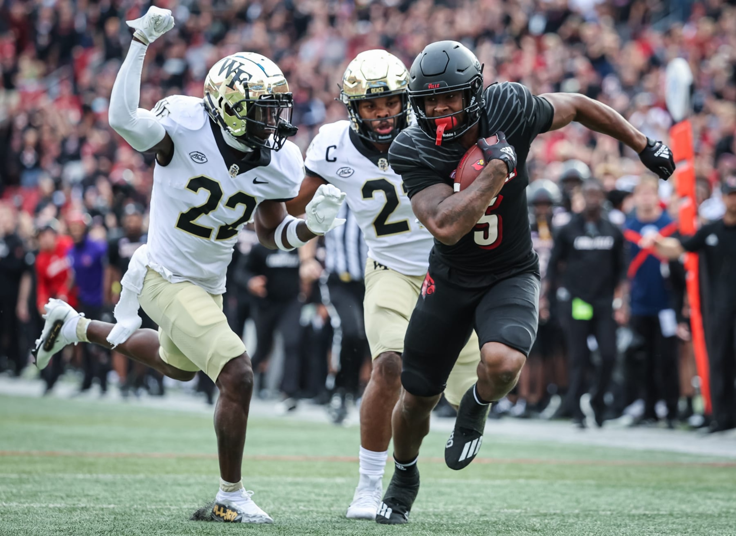LOUISVILLE, KY - OCTOBER 29: Marshon Ford #5 of the Louisville Cardinals runs the ball as AJ Williams #22 of the Wake Forest Demon Deacons closes in for the tackle during the first half at Cardinal Stadium on October 29, 2022 in Louisville, Kentucky. (Photo by Michael Hickey/Getty Images)