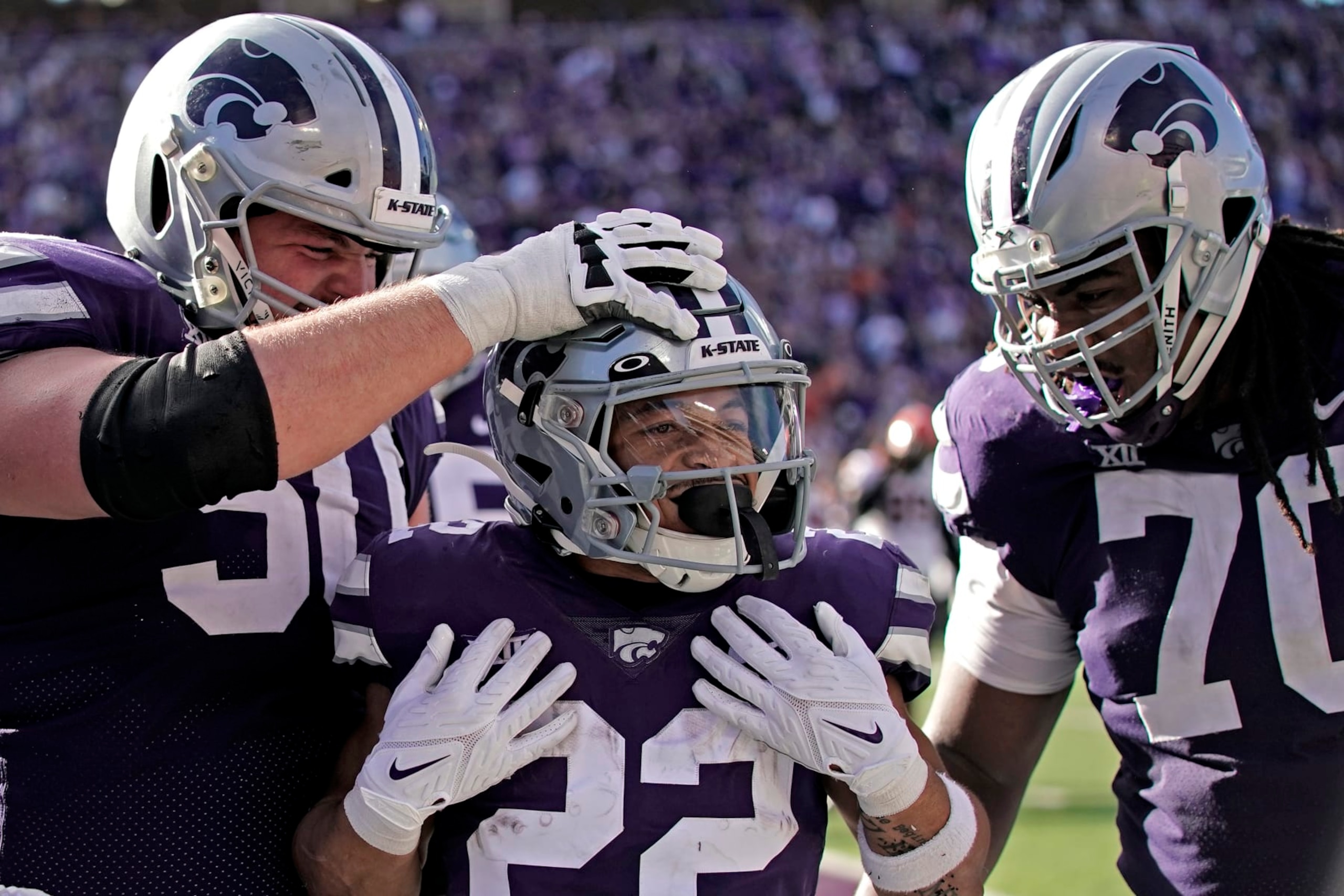 Kansas State running back Deuce Vaughn, center, celebrates with offensive linemen Cooper Beebe (50) and KT Leveston (70) after scoring a touchdown during the first half of an NCAA college football game against Oklahoma State Saturday, Oct. 29, 2022, in Manhattan, Kan. (AP Photo/Charlie Riedel)