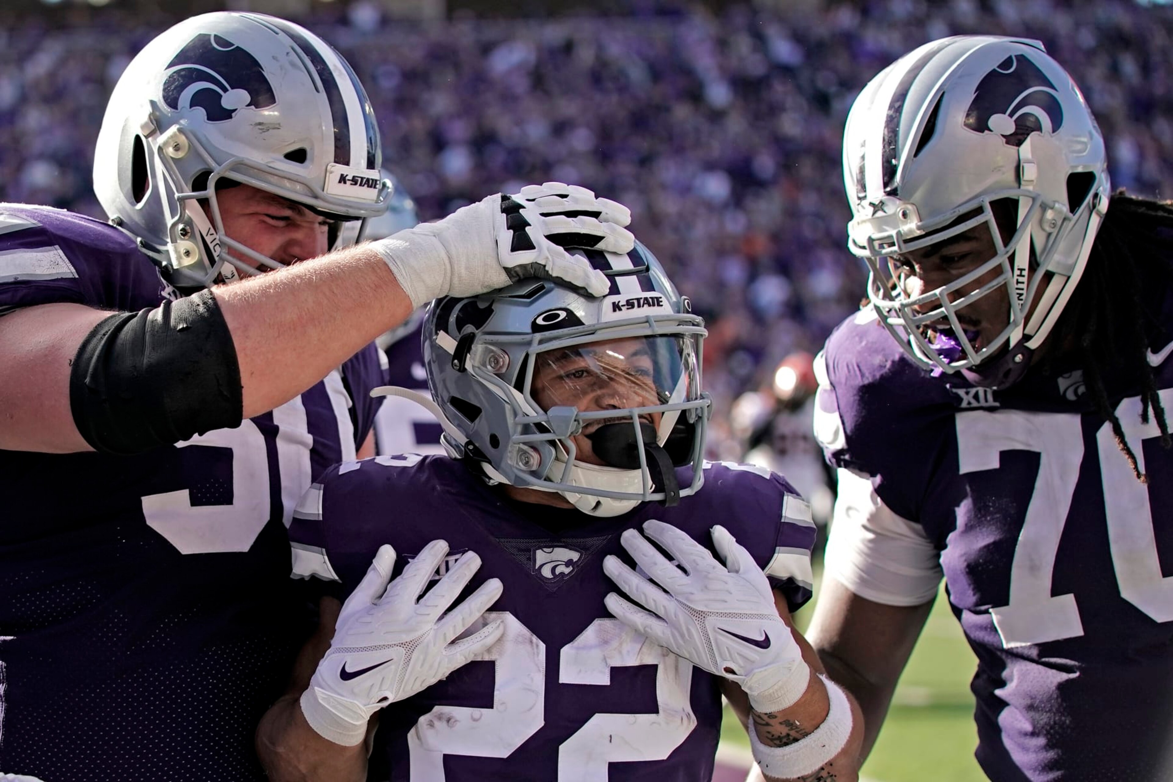 Kansas State running back Deuce Vaughn, center, celebrates with offensive linemen Cooper Beebe (50) and KT Leveston (70) after scoring a touchdown during the first half of an NCAA college football game against Oklahoma State Saturday, Oct. 29, 2022, in Manhattan, Kan. (AP Photo/Charlie Riedel)