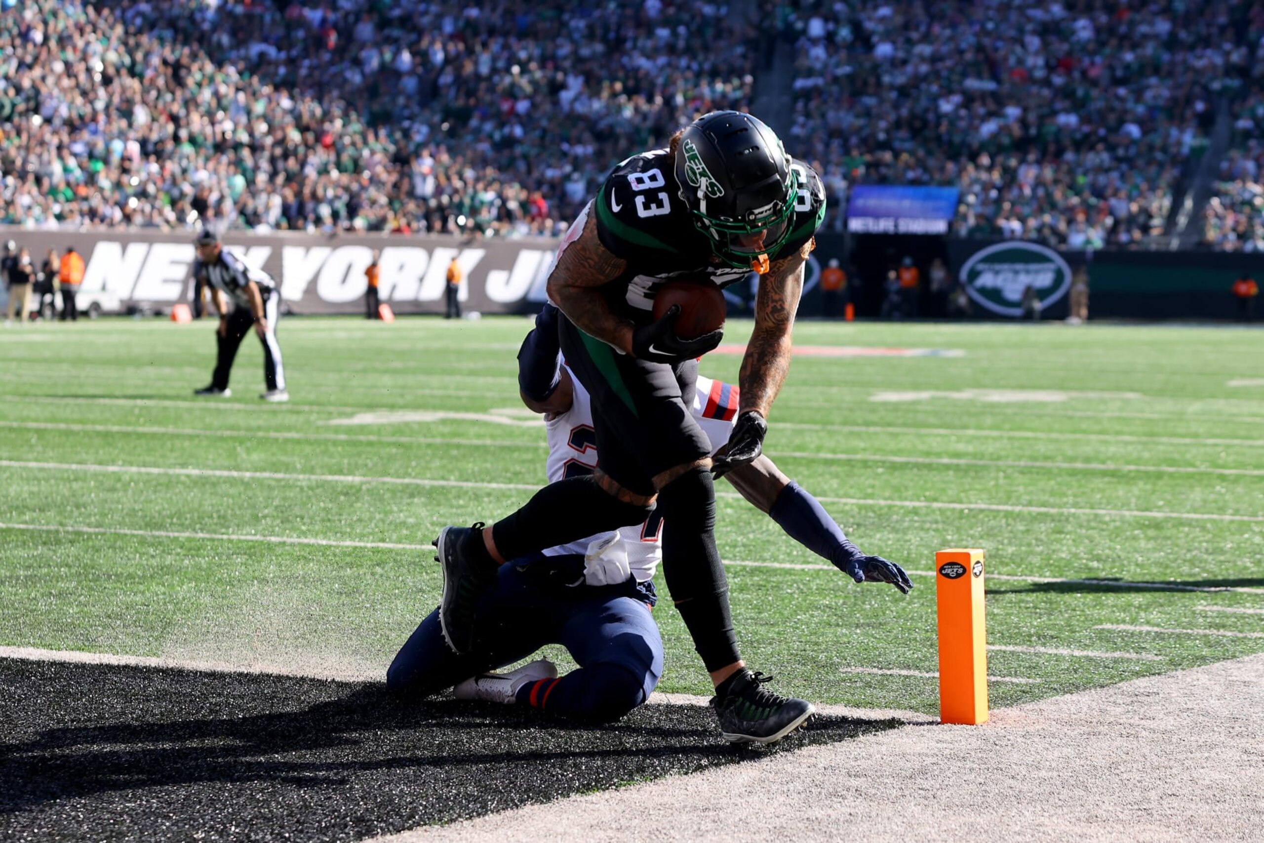 EAST RUTHERFORD, NEW JERSEY - OCTOBER 30: Tyler Conklin #83 of the New York Jets scores a touchdown as Joshuah Bledsoe #24 of the New England Patriots defends during the first half at MetLife Stadium on October 30, 2022 in East Rutherford, New Jersey. (Photo by Mike Stobe/Getty Images)