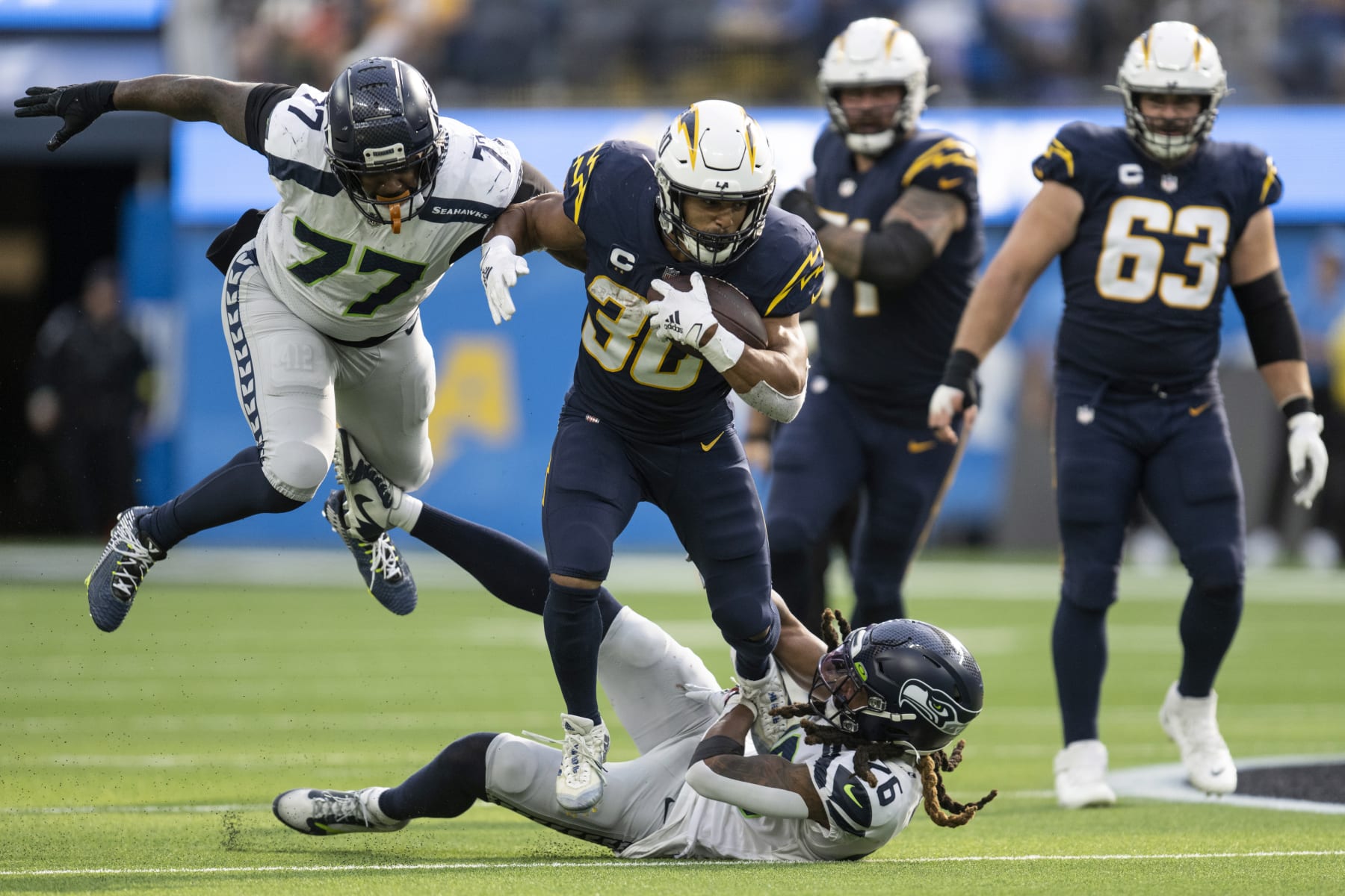 Seattle Seahawks defensive tackle Quinton Jefferson (77) and safety Ryan Neal (26) tackle Los Angeles Chargers running back Austin Ekeler (30) during an NFL football game, Sunday, Oct. 23, 2022, in Inglewood, Calif. (AP Photo/Kyusung Gong)