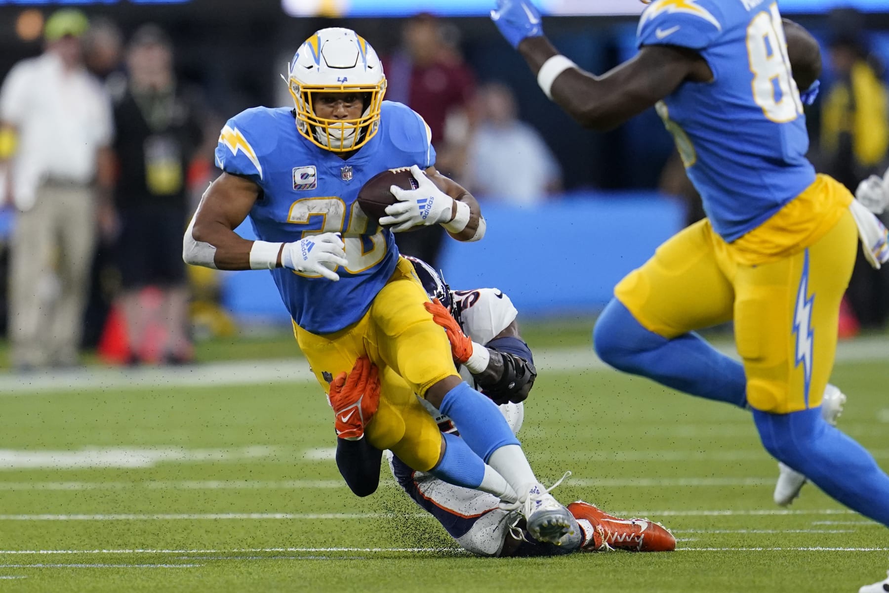 Los Angeles Chargers running back Austin Ekeler, front, is hit by Denver Broncos linebacker Jonas Griffith during the first half of an NFL football game, Monday, Oct. 17, 2022, in Inglewood, Calif. (AP Photo/Marcio Jose Sanchez)