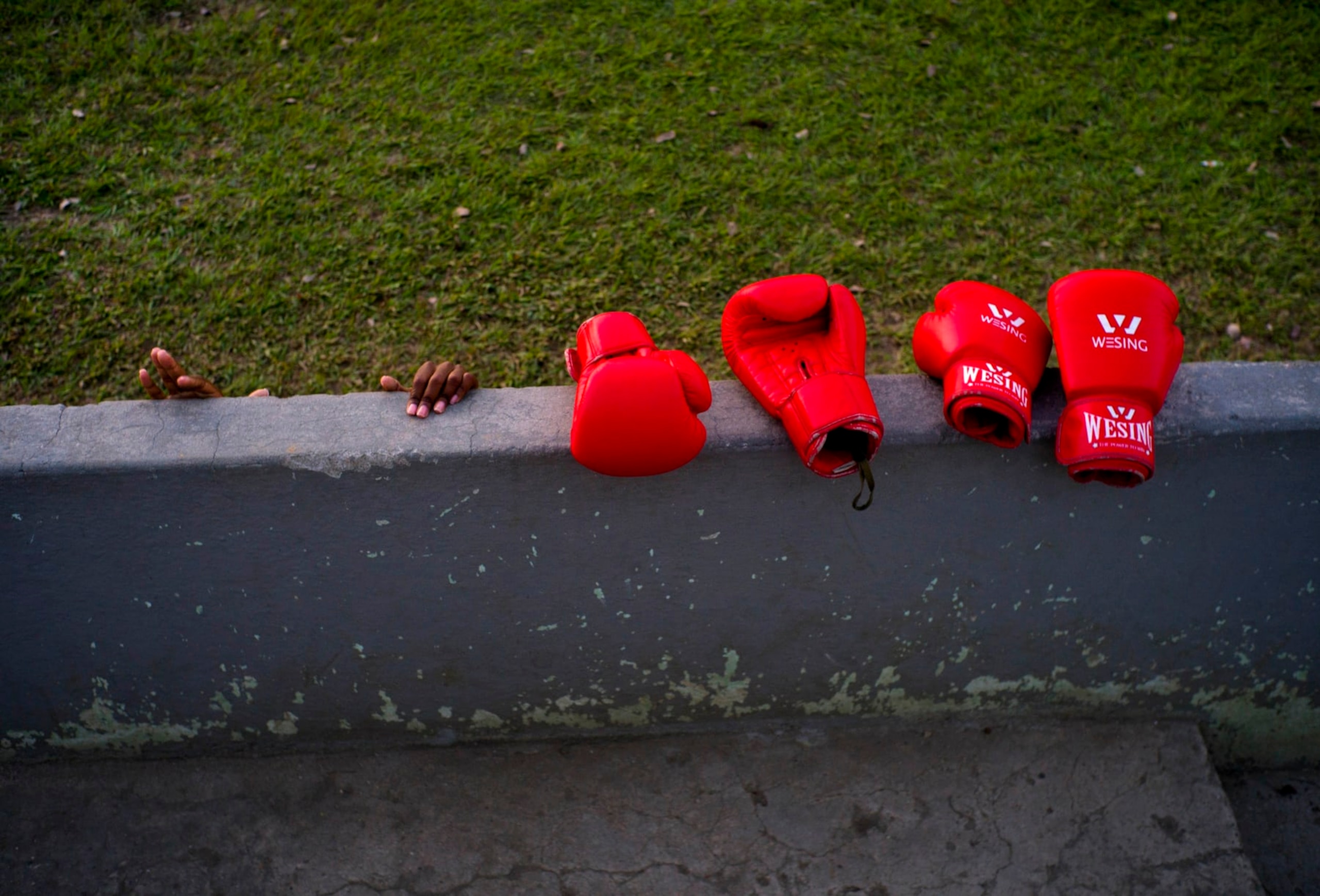 In this Jan. 19, 2017 photo, boxer Legnis Cala's hands grab a wall, next to boxing gloves during a warm-up prior to a training session, in Havana, Cuba. Officials have said they're analyzing whether to allow women to box and say they are carrying out medical studies to understand the impact of blows to a woman's body and whether such action is "appropriate." (AP Photo/Ramon Espinosa)