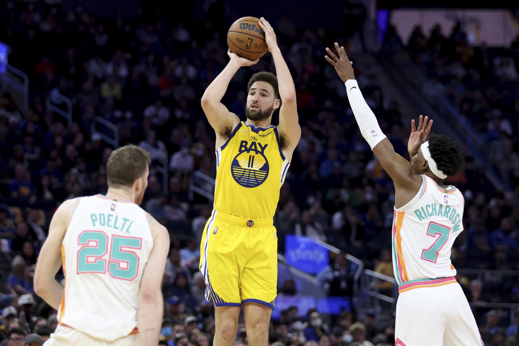 Golden State Warriors guard Klay Thompson (11) shoots against San Antonio Spurs center Jakob Poeltl (25) and guard Josh Richardson (7) during the second half of an NBA basketball game in San Francisco, Sunday, March 20, 2022. (AP Photo/Jed Jacobsohn)