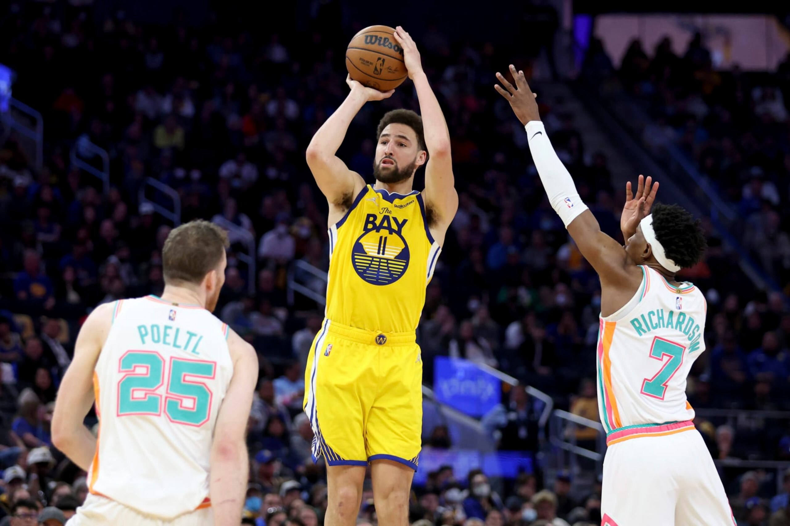 Golden State Warriors guard Klay Thompson (11) shoots against San Antonio Spurs center Jakob Poeltl (25) and guard Josh Richardson (7) during the second half of an NBA basketball game in San Francisco, Sunday, March 20, 2022. (AP Photo/Jed Jacobsohn)